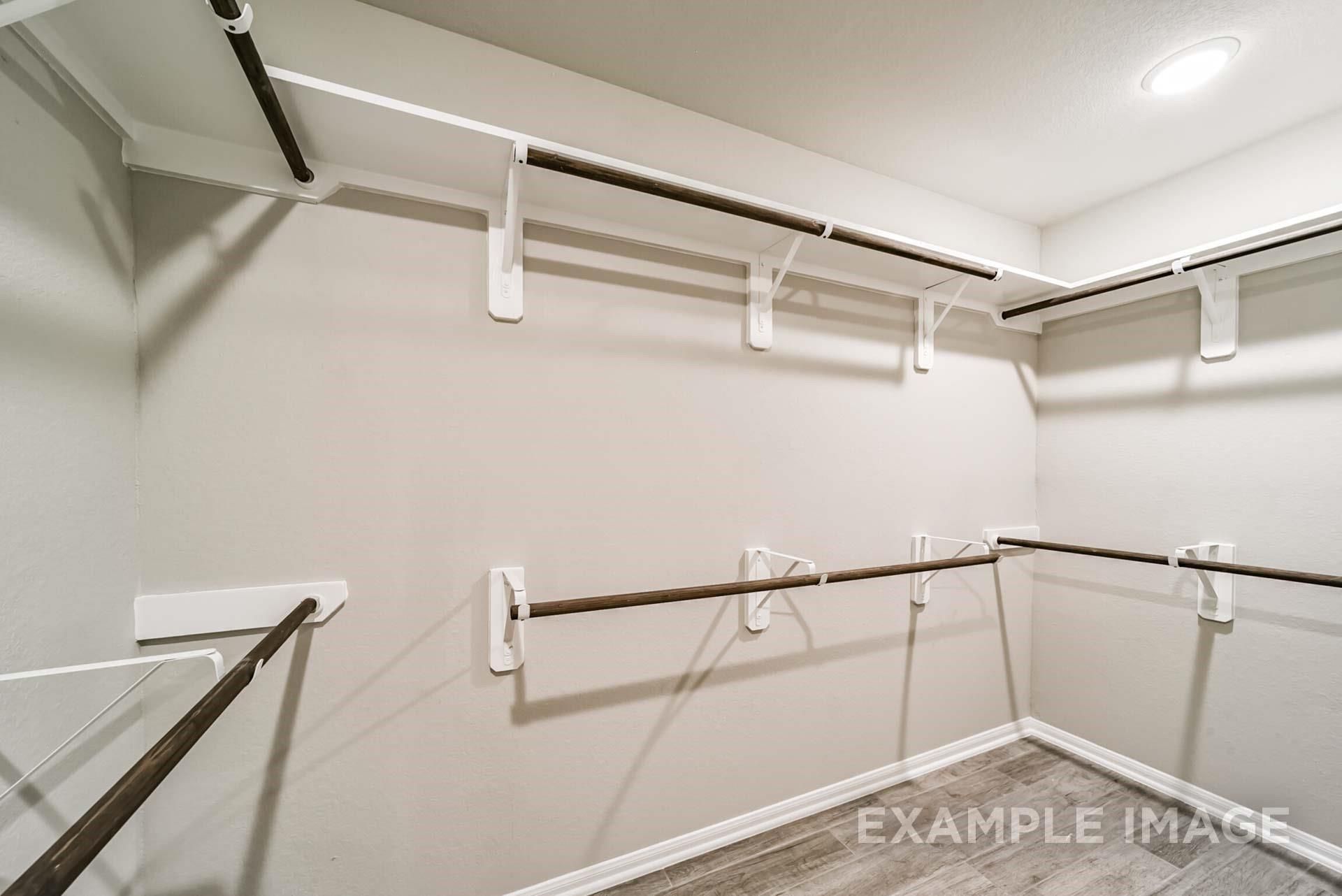 Spacious walk-in closet with tiered shelving in The Riviera A floor plan by Davidson Homes in Emberly, Beasley, Texas.