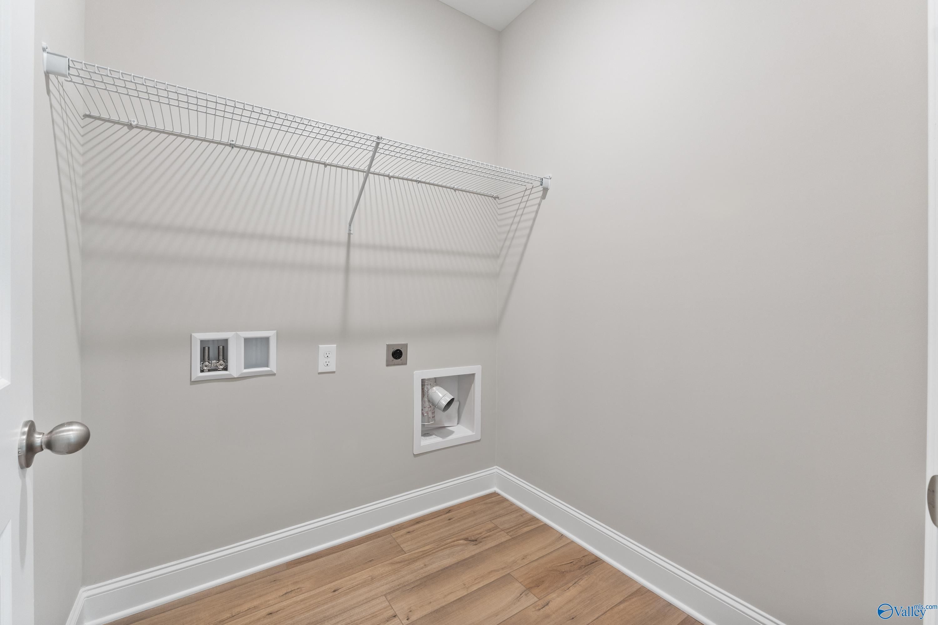 Spacious laundry room with wire shelving, hookups, and hardwood floors in The Franklin 3-bedroom home, Spragins Cove, Huntsville, Alabama