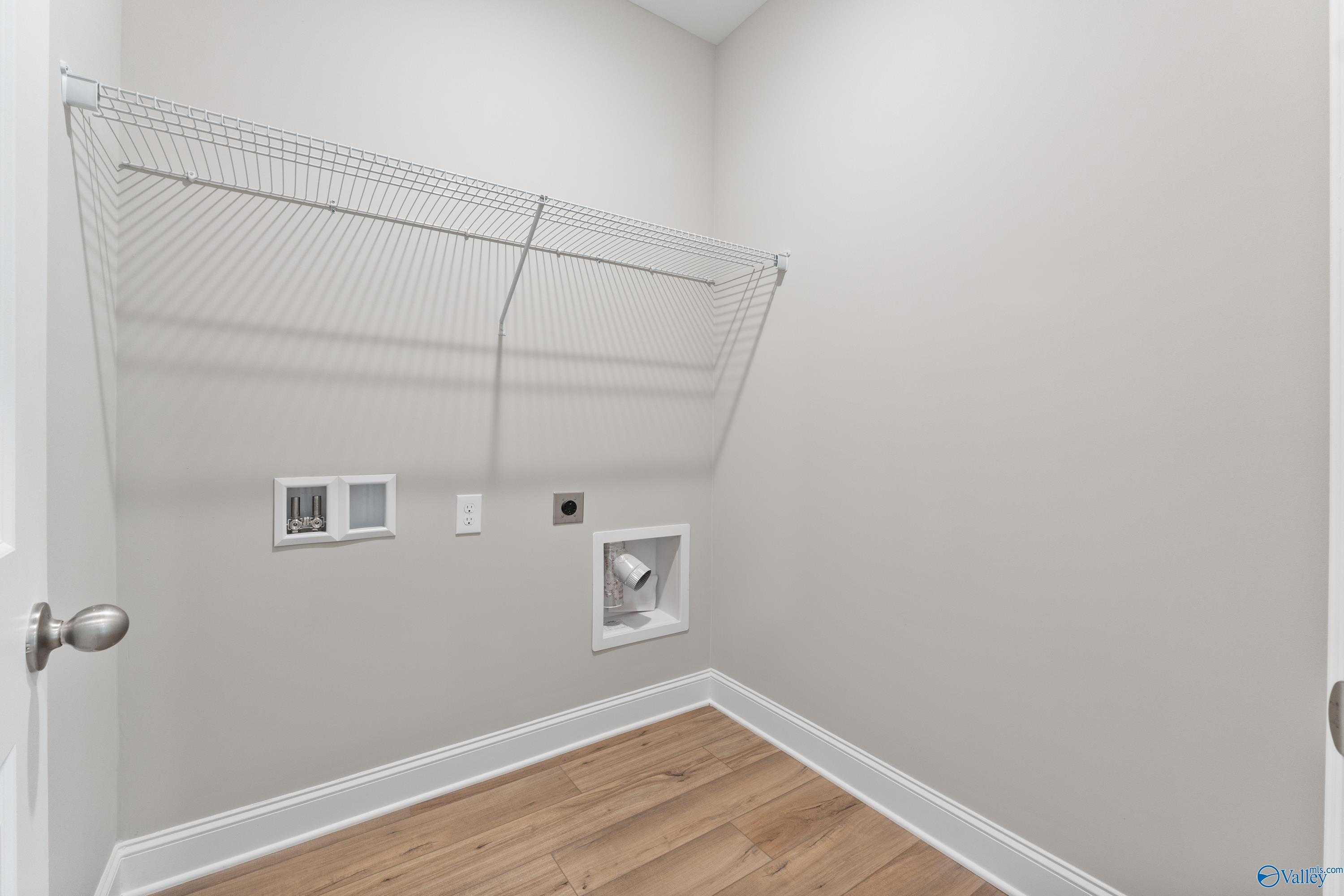 Spacious laundry room with wire shelving, hookups, and hardwood floors in The Franklin 3-bedroom home, Spragins Cove, Huntsville, Alabama