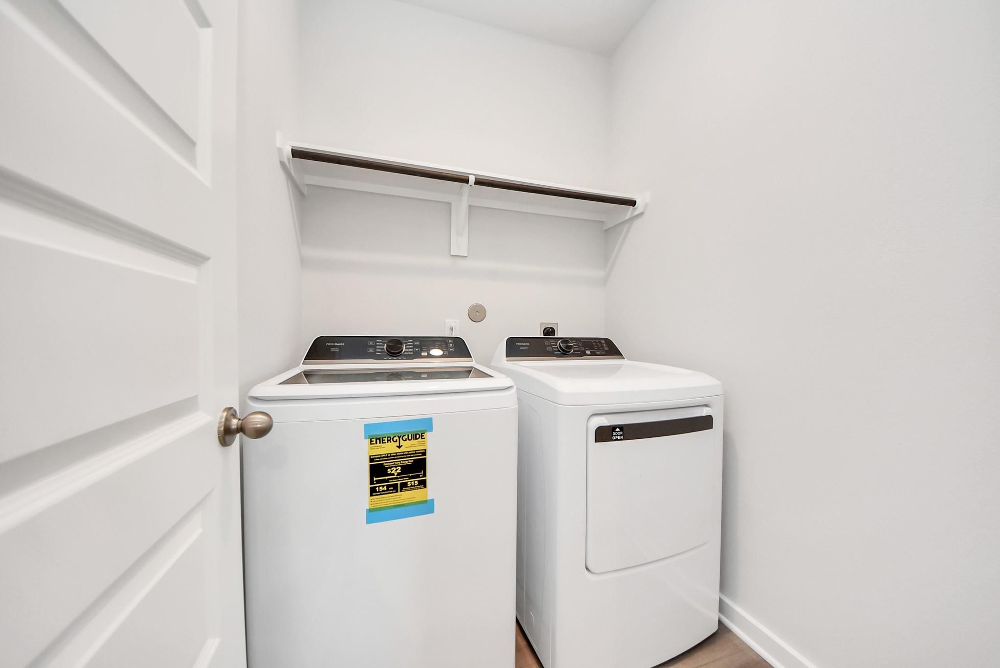 Laundry room with washer and dryer and built-in shelving in The Blanco E floor plan at The Villages at WestPointe, Texas.