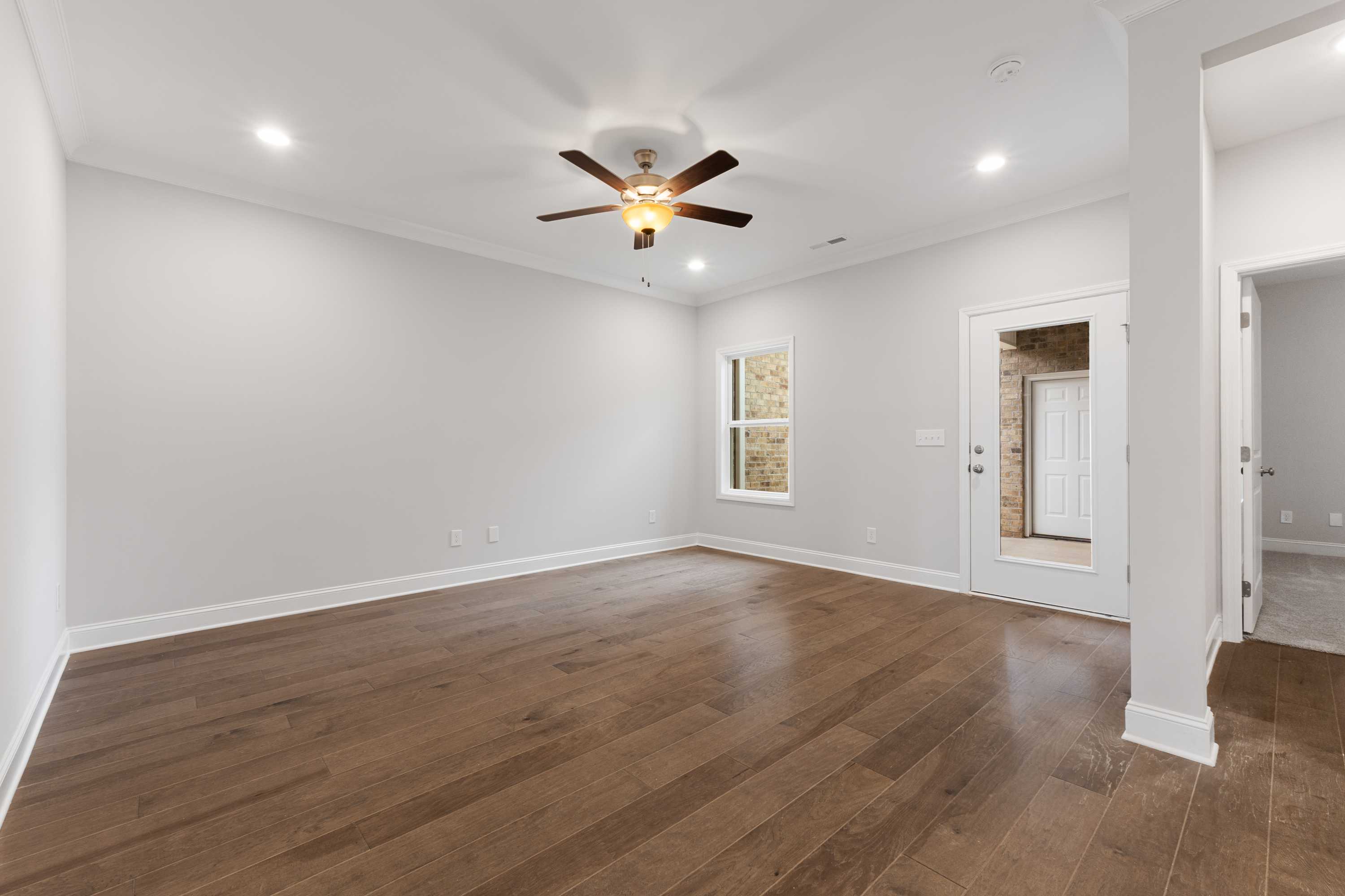 Spacious master bedroom in The Copeland B with hardwood floors, ceiling fan, gray walls, and bath access