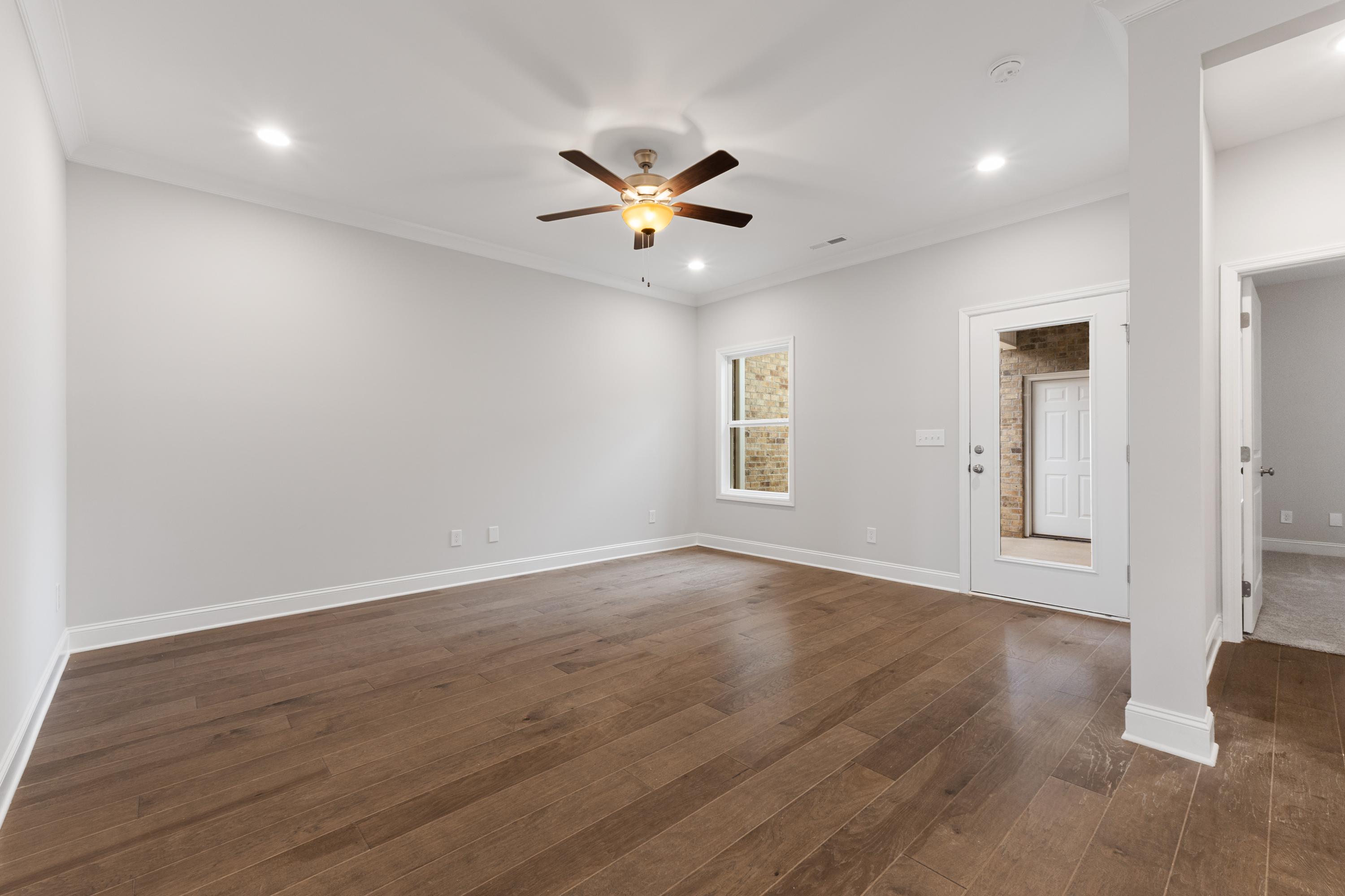Spacious master bedroom in The Copeland C with hardwood floors, ceiling fan, and large window