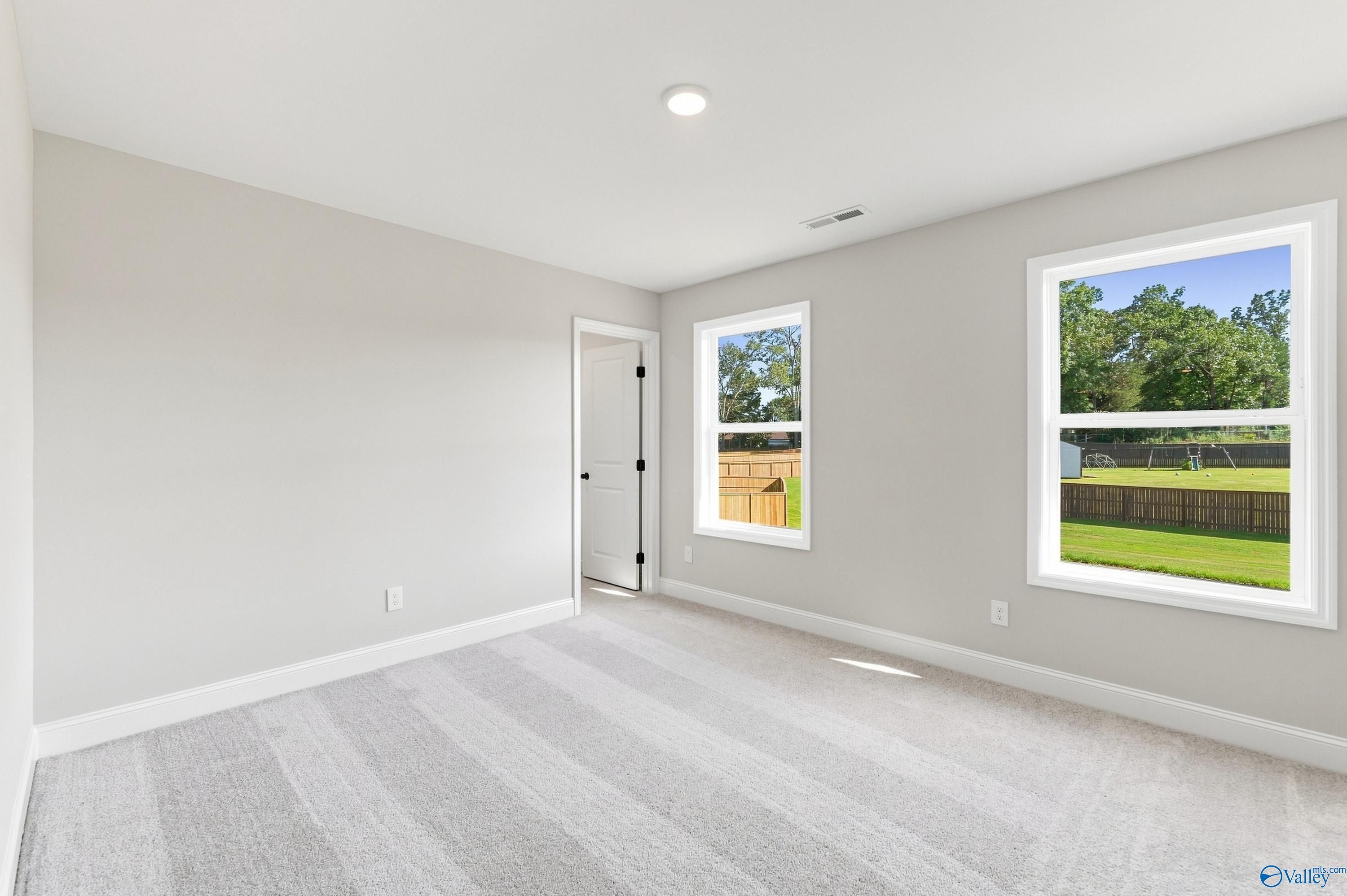 Bright carpeted bedroom with two windows overlooking fenced backyard in Davidson Homes Chelsea B, New Market, Alabama