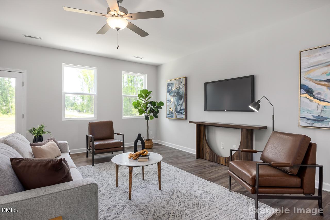Bright, modern living room with leather chairs and wall-mounted TV in The Grace A home at Gregory Village, Lillington, NC.
