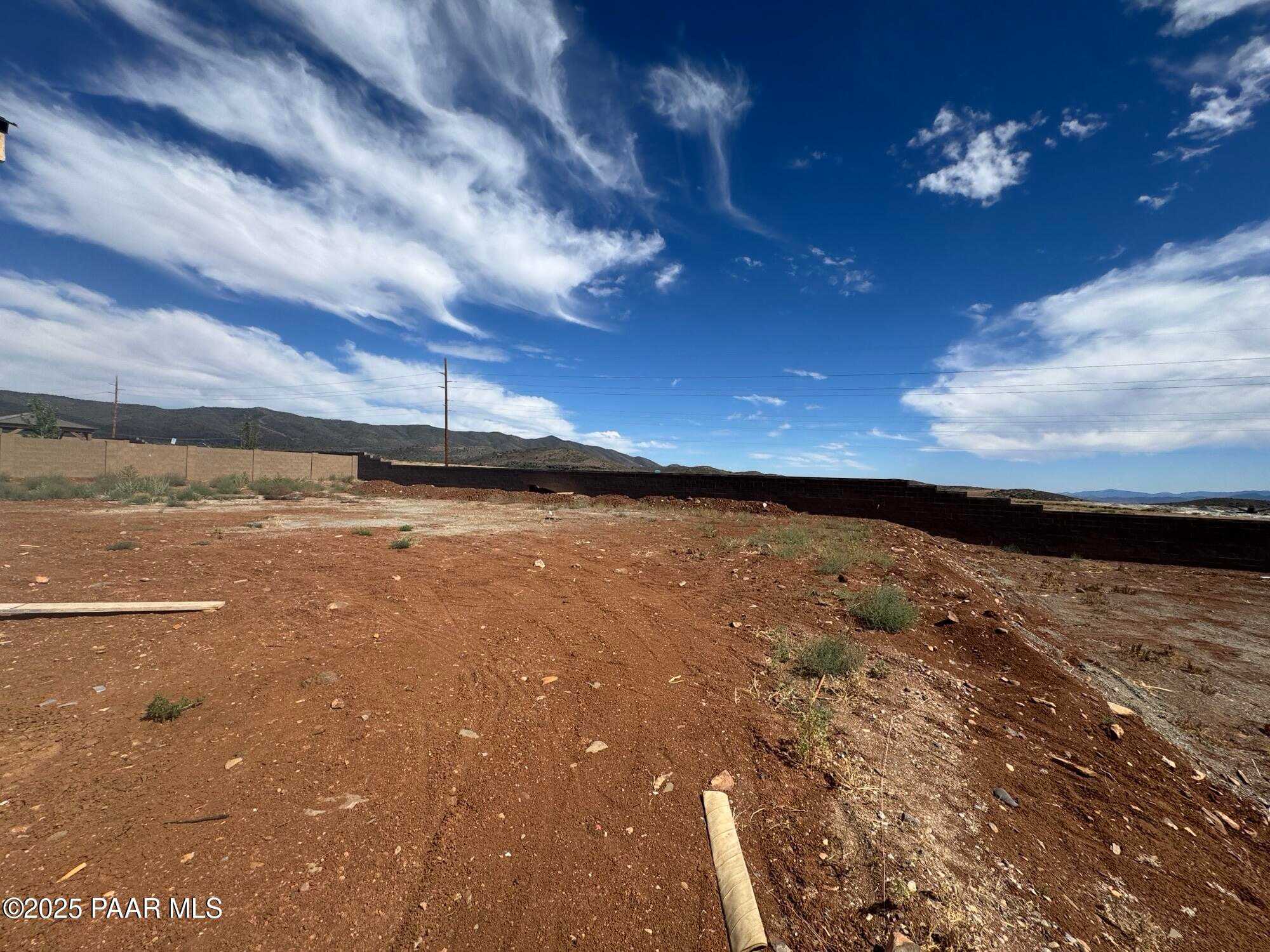 Expansive red dirt construction site with block walls, utility poles, and mountain views in Morningstar, Prescott Valley, Arizona - The Sunrise A by Evermore Homes