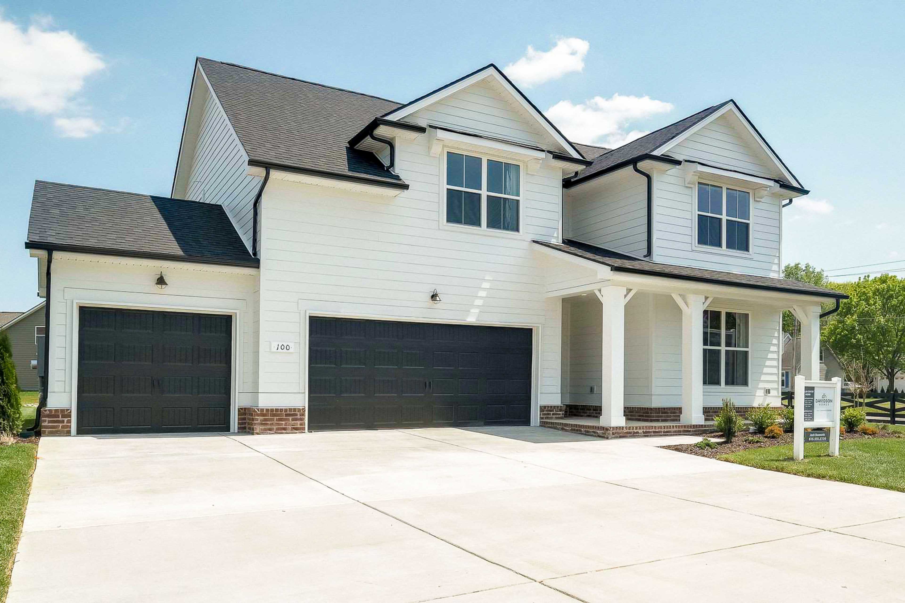 Modern two-story home exterior at The Meadows in Smyrna TN with white siding, covered porch, brick accents, and two-car garage