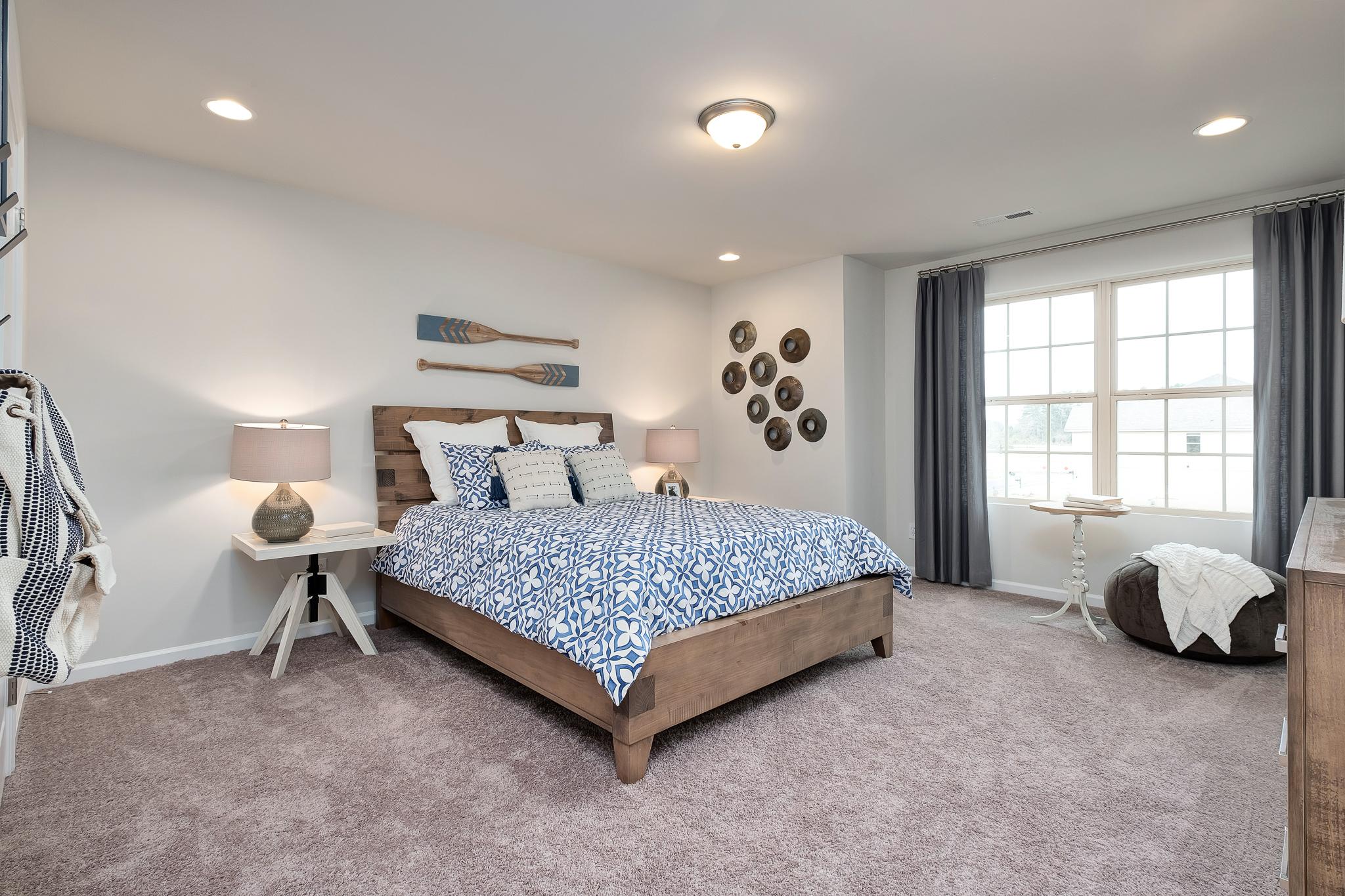 Cozy nautical bedroom with wooden bed, blue floral bedding, oar decor at The Reserve at Overton, Hampton Cove AL