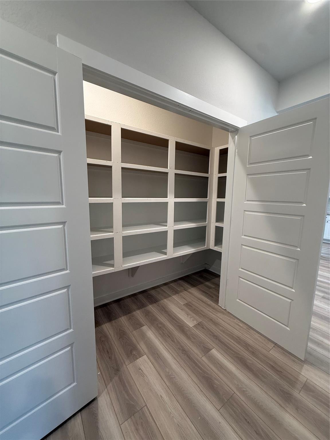 Spacious walk-in pantry with white custom shelving in The Sorrento E floor plan by Davidson Homes in Sundance Cove, Crosby.