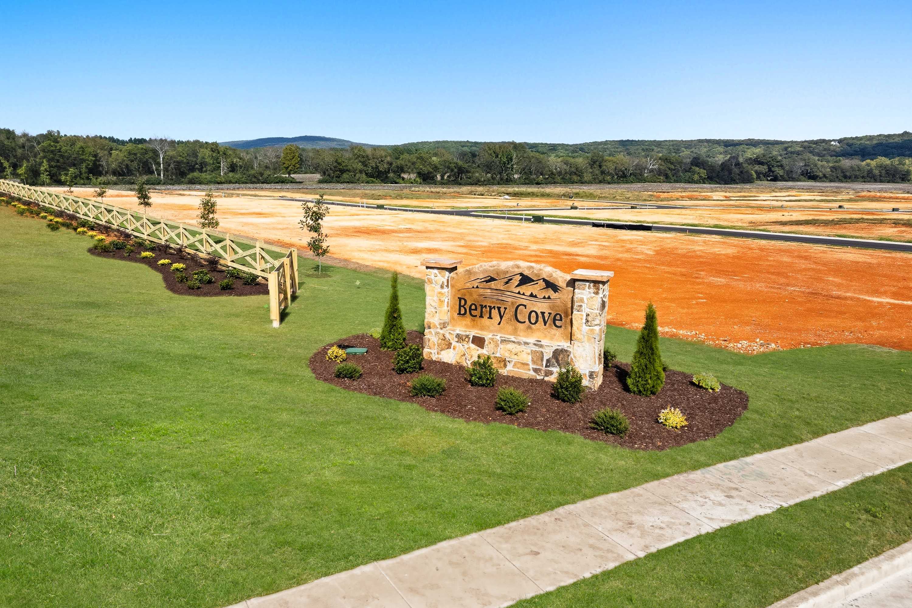 Berry Cove entrance sign in New Market Alabama with stone pillar mountain logo landscaped shrubs and wooded hills backdrop