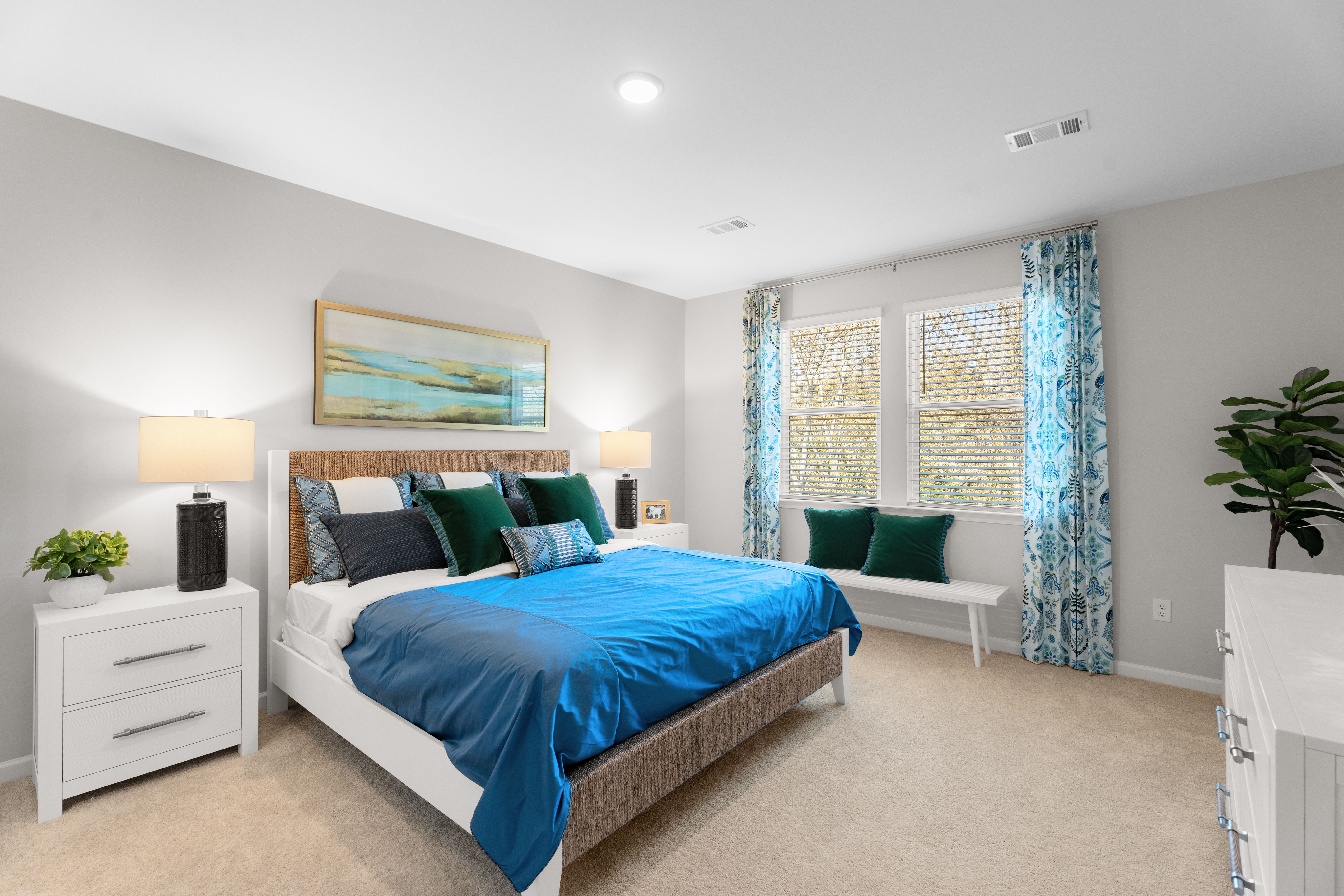 Owners bedroom with king size bed, two white side tables and a dresser