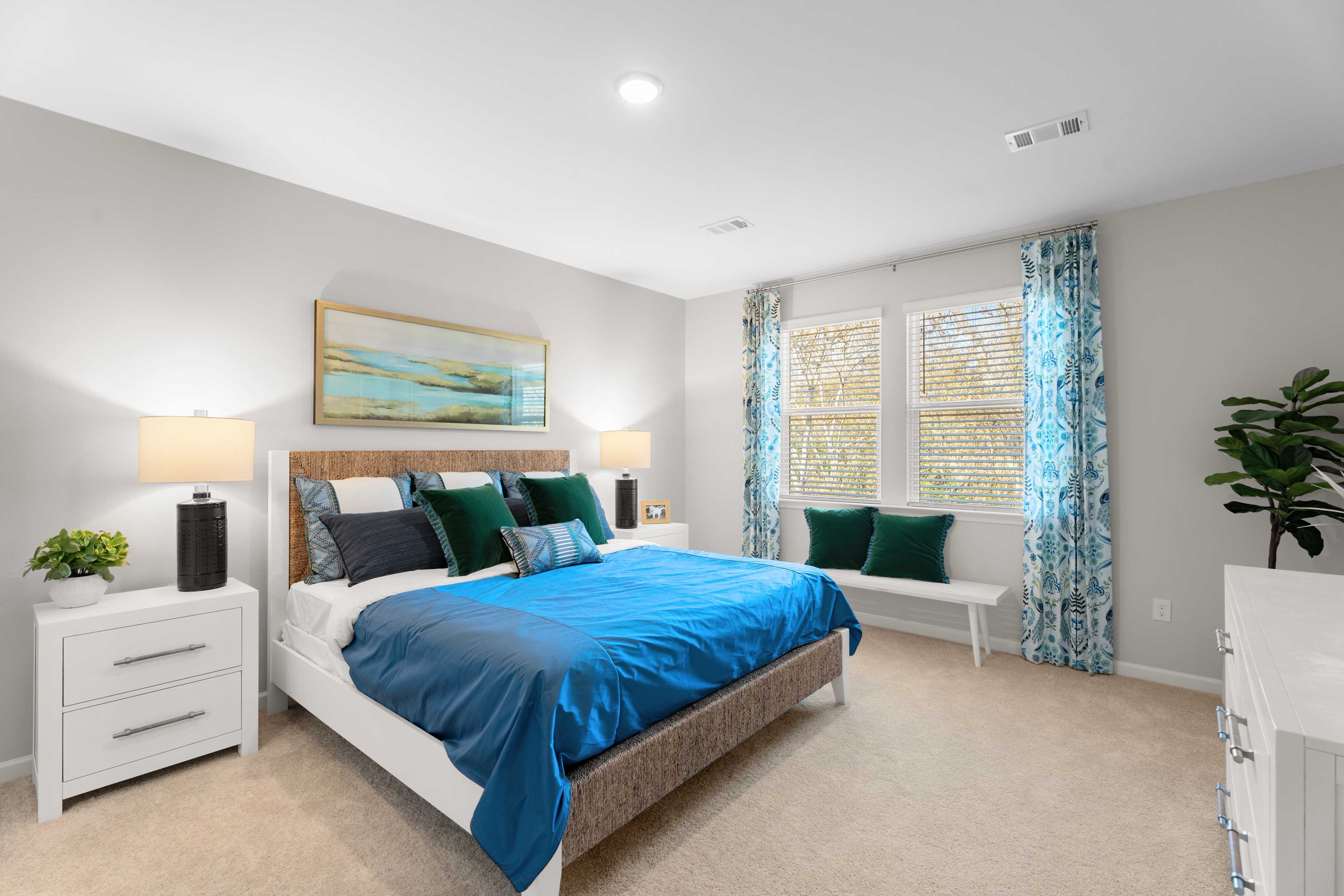 Owners bedroom with king size bed, two white side tables and a dresser