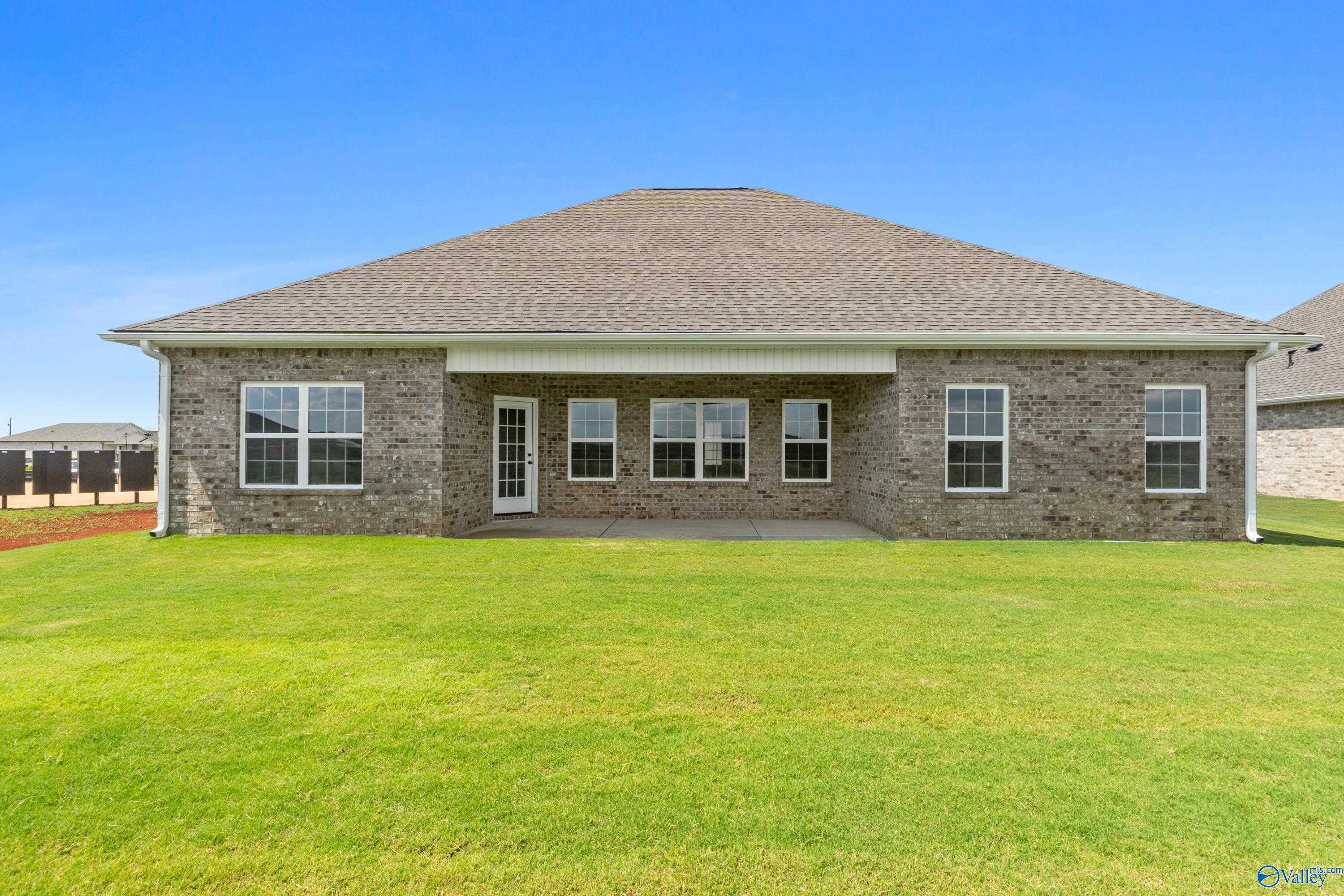Brick single-story home with covered back patio, French doors, and lush green yard in Kendall Farms, Toney, Alabama