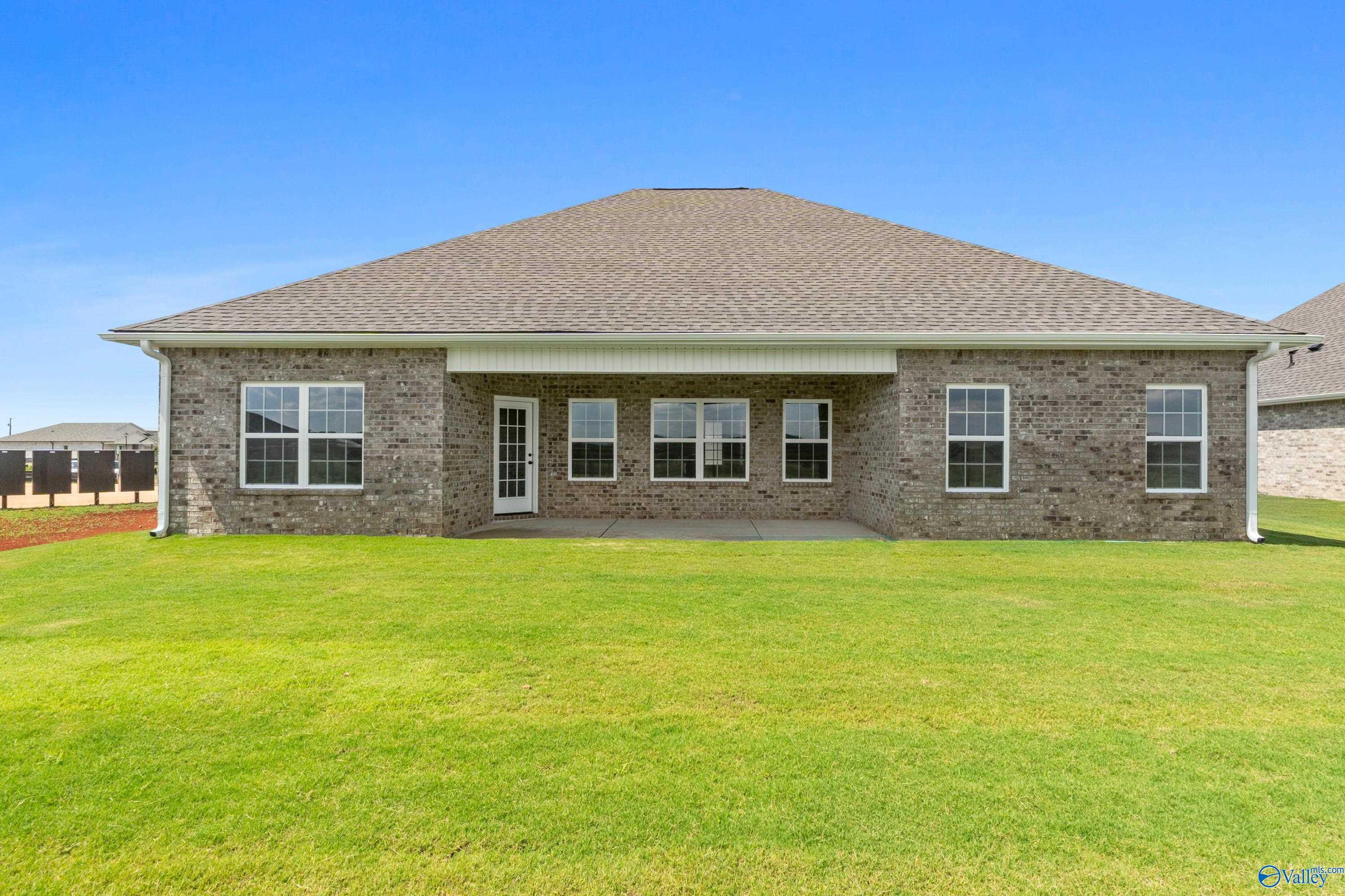 Rear view of Davidson Homes The Rockford B with covered patio, large windows, and lush green lawn in Kendall Farms, Toney, Alabama