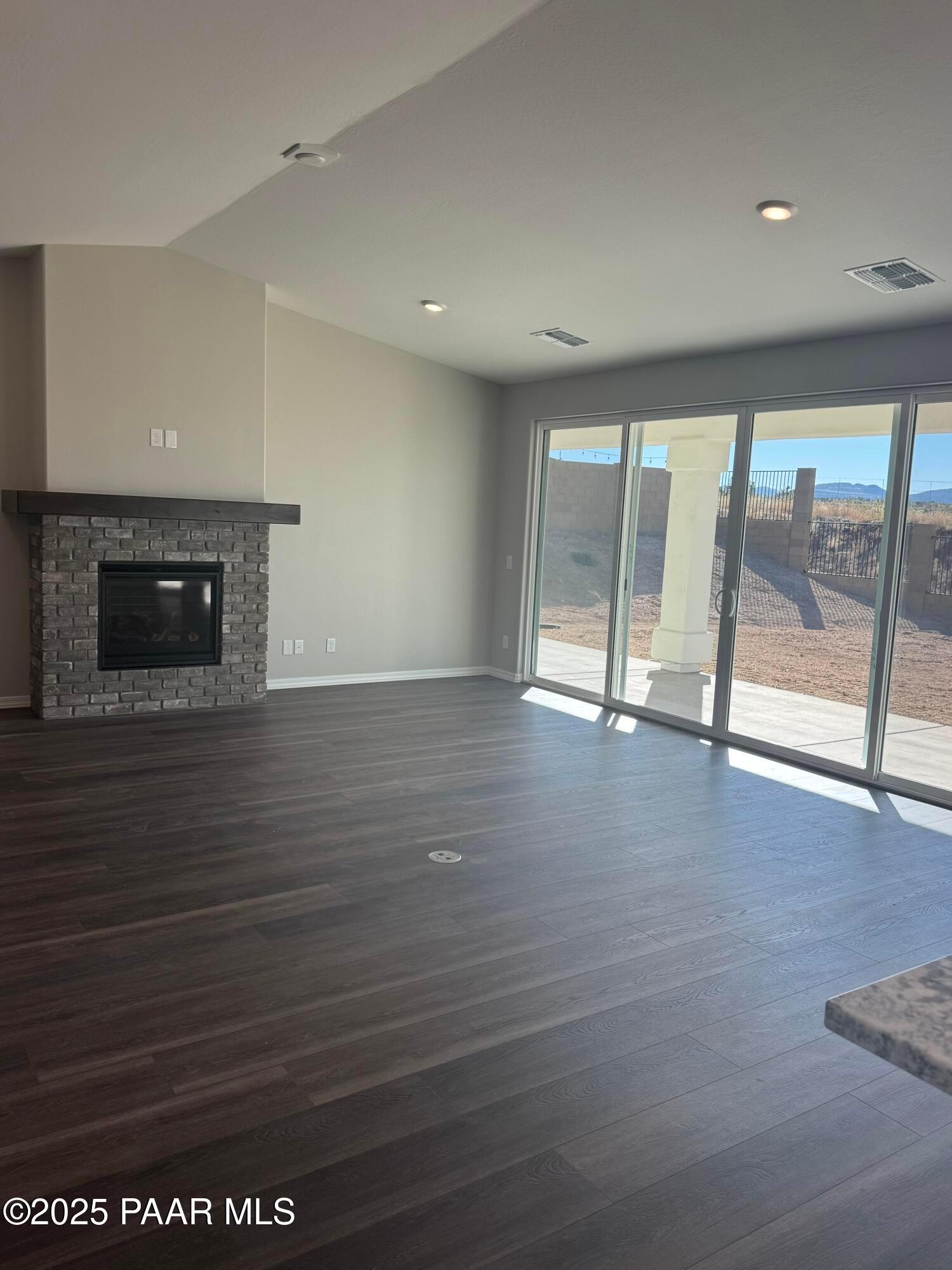 Spacious living room with stone gas fireplace, sliding doors to desert patio, and mountain views in Davidson Homes The Monarch E, Prescott Arizona