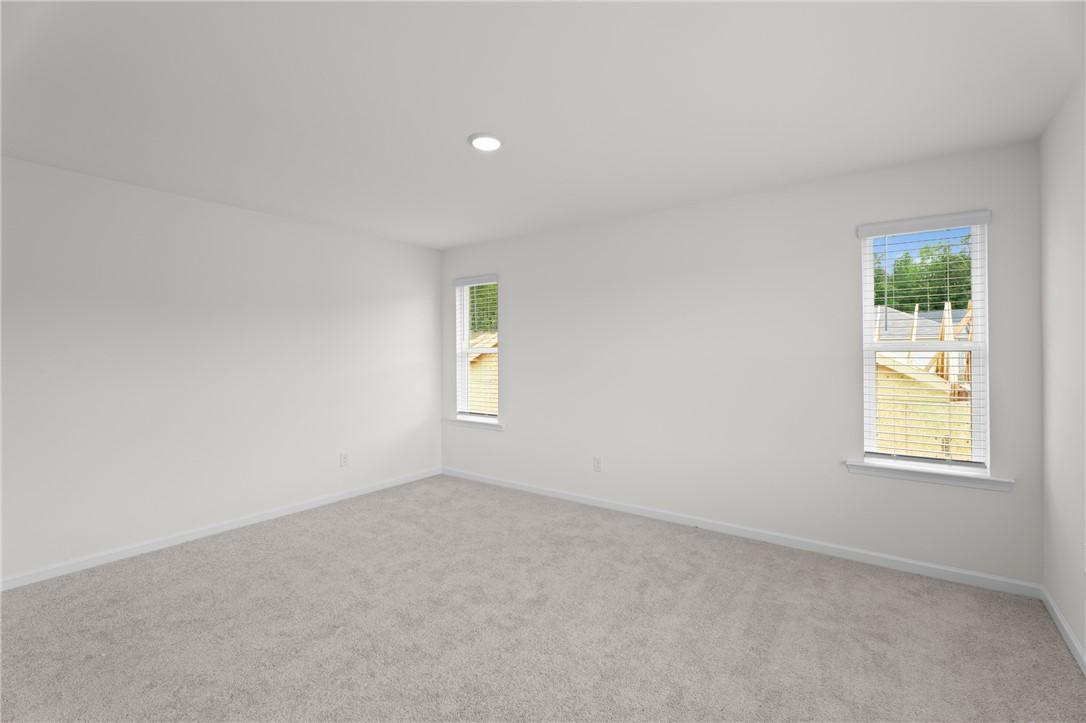 Bright, spacious bedroom with neutral carpet in The Stella D floor plan by Evermore Homes in Silver Oak, Cusseta, Alabama.