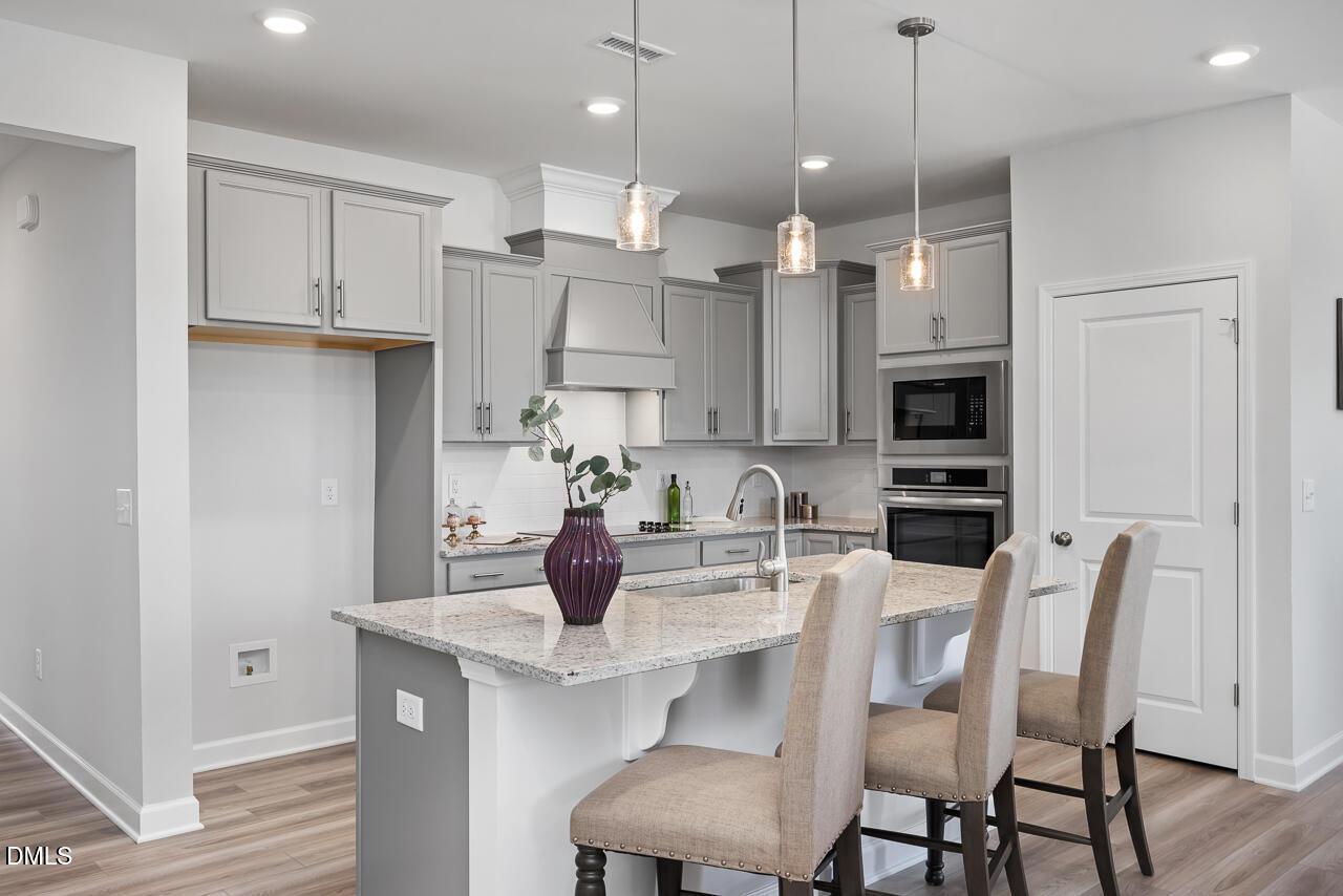 Modern gray kitchen with granite island, stainless appliances, pendant lights in The Daphne D home, Lillington, NC