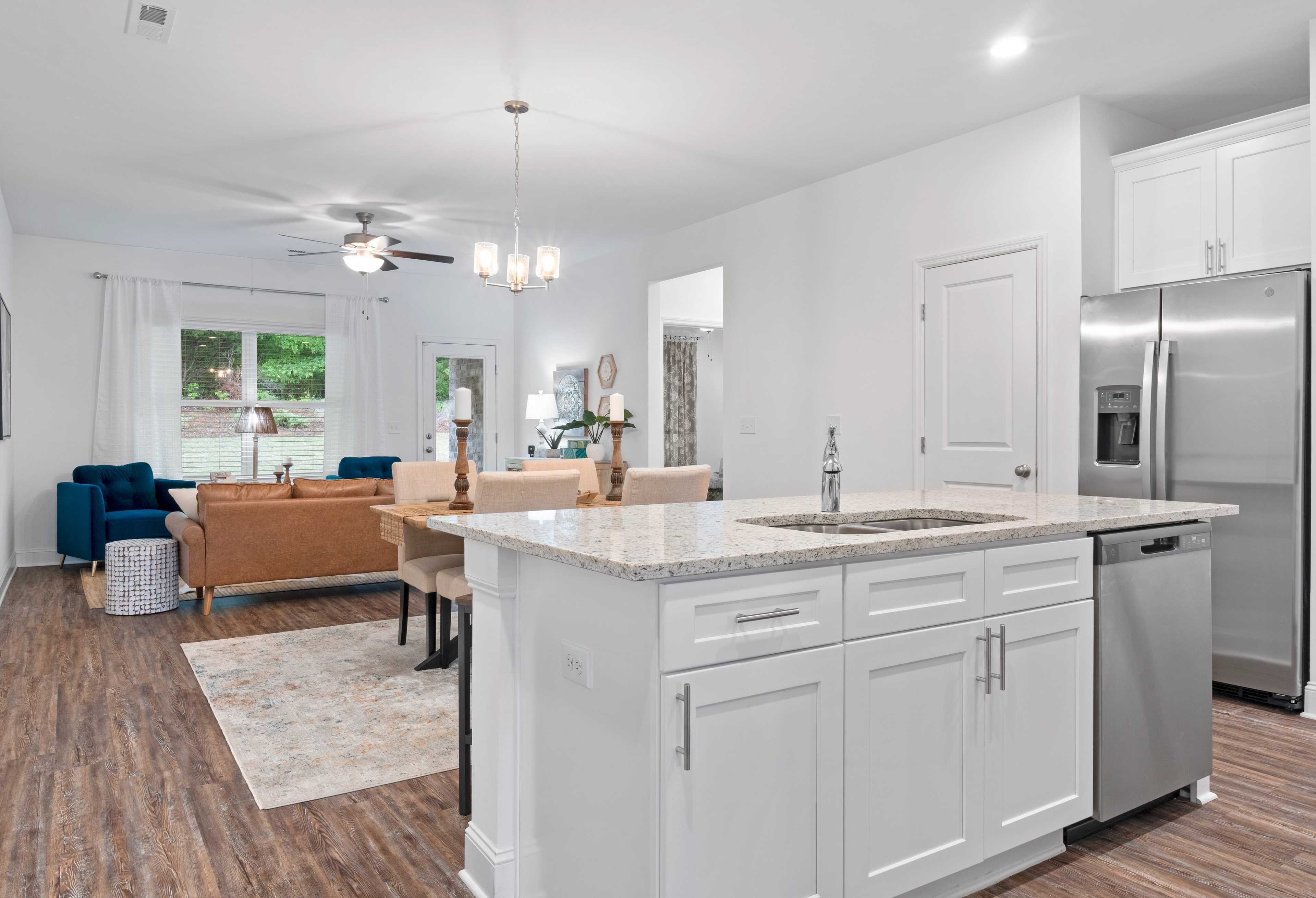 Spacious open-concept kitchen in The Cumberland home with white cabinets, quartz island, stainless appliances, and adjacent dining area
