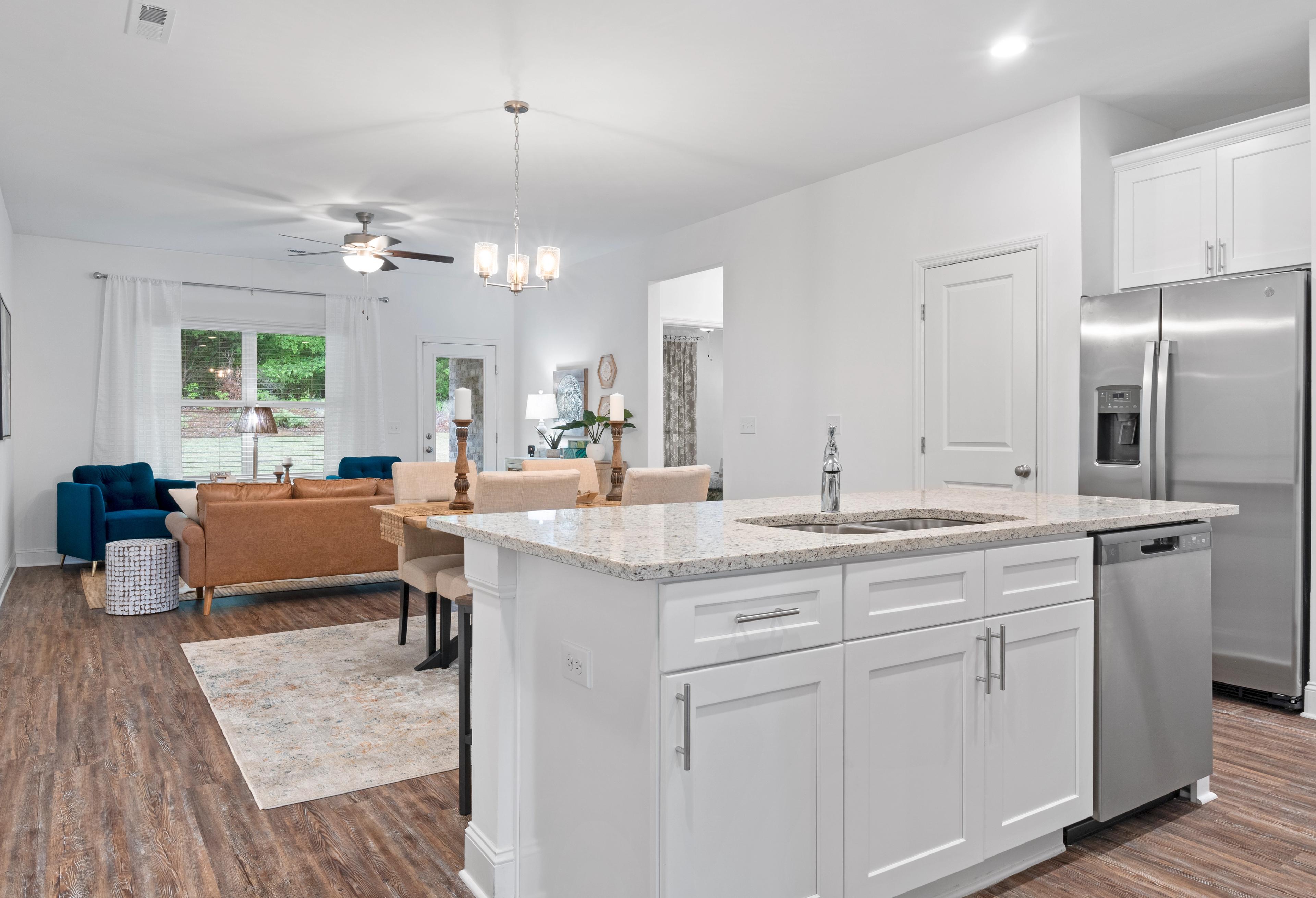Spacious open-concept kitchen in The Cumberland home with white cabinets, quartz island, stainless appliances, and adjacent dining area