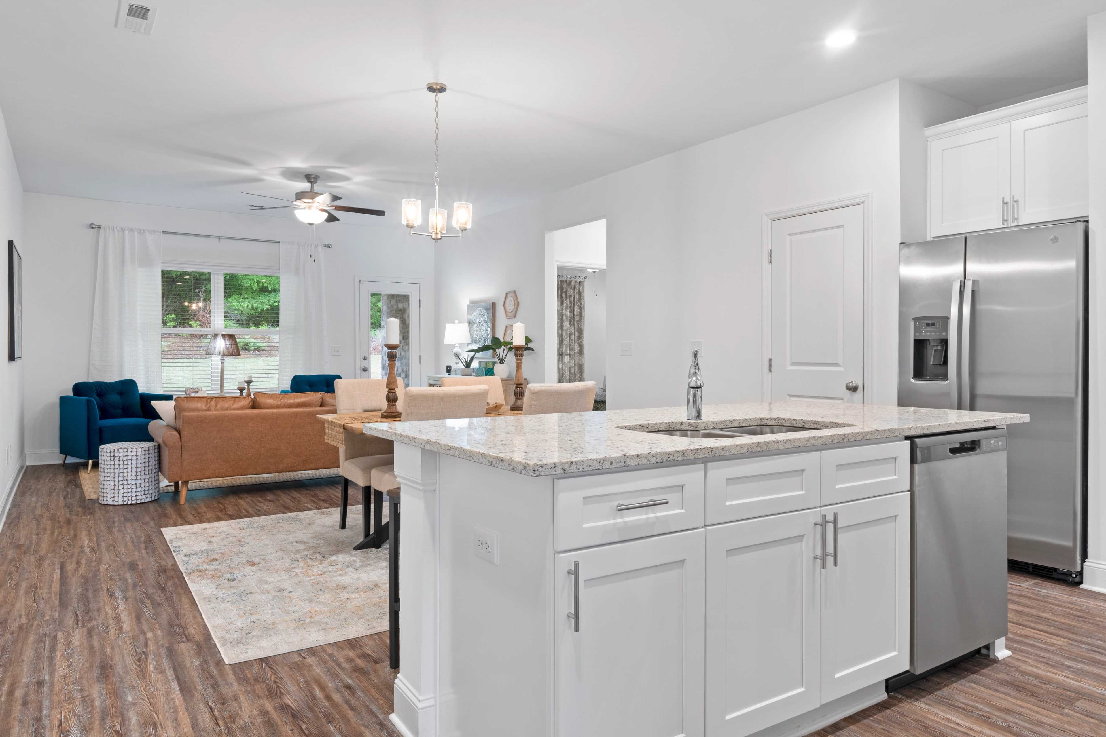 Open-concept kitchen and dining area at The Retreat at Hollon Meadow in Decatur AL with white cabinets, quartz island, hardwood floors, and stainless appliances