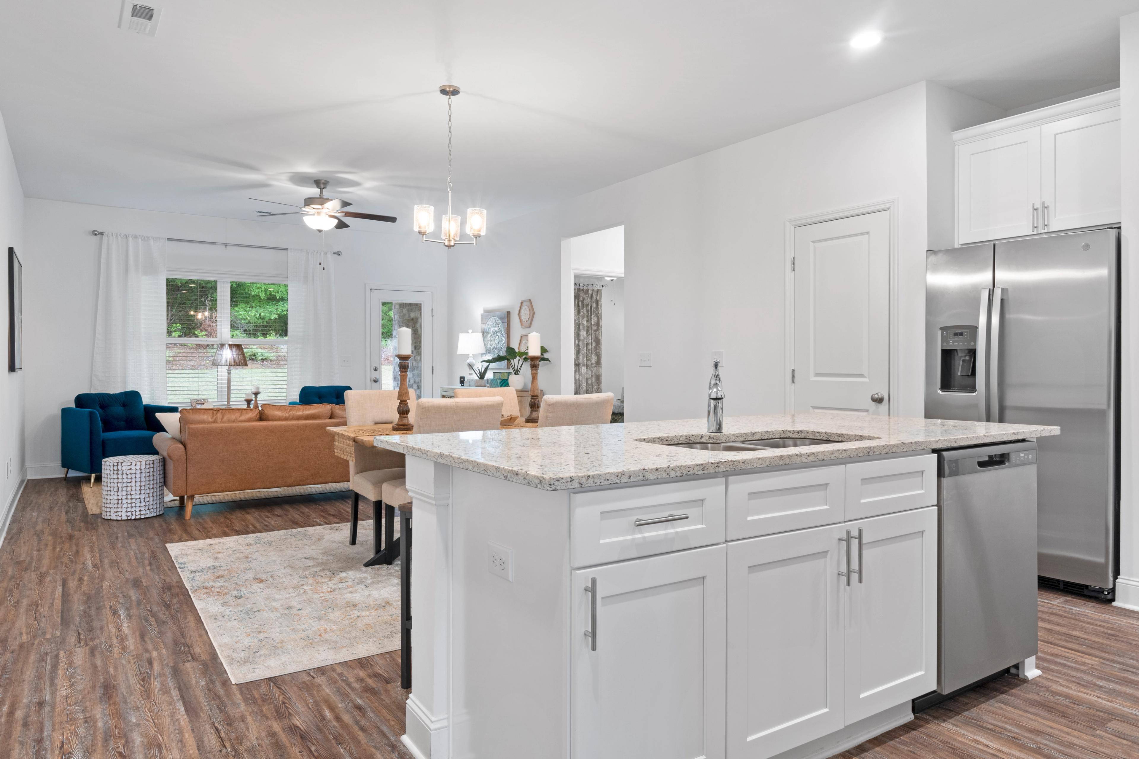 Spacious open-concept kitchen in The Cumberland home with white cabinets, quartz island, stainless appliances, and adjacent dining area