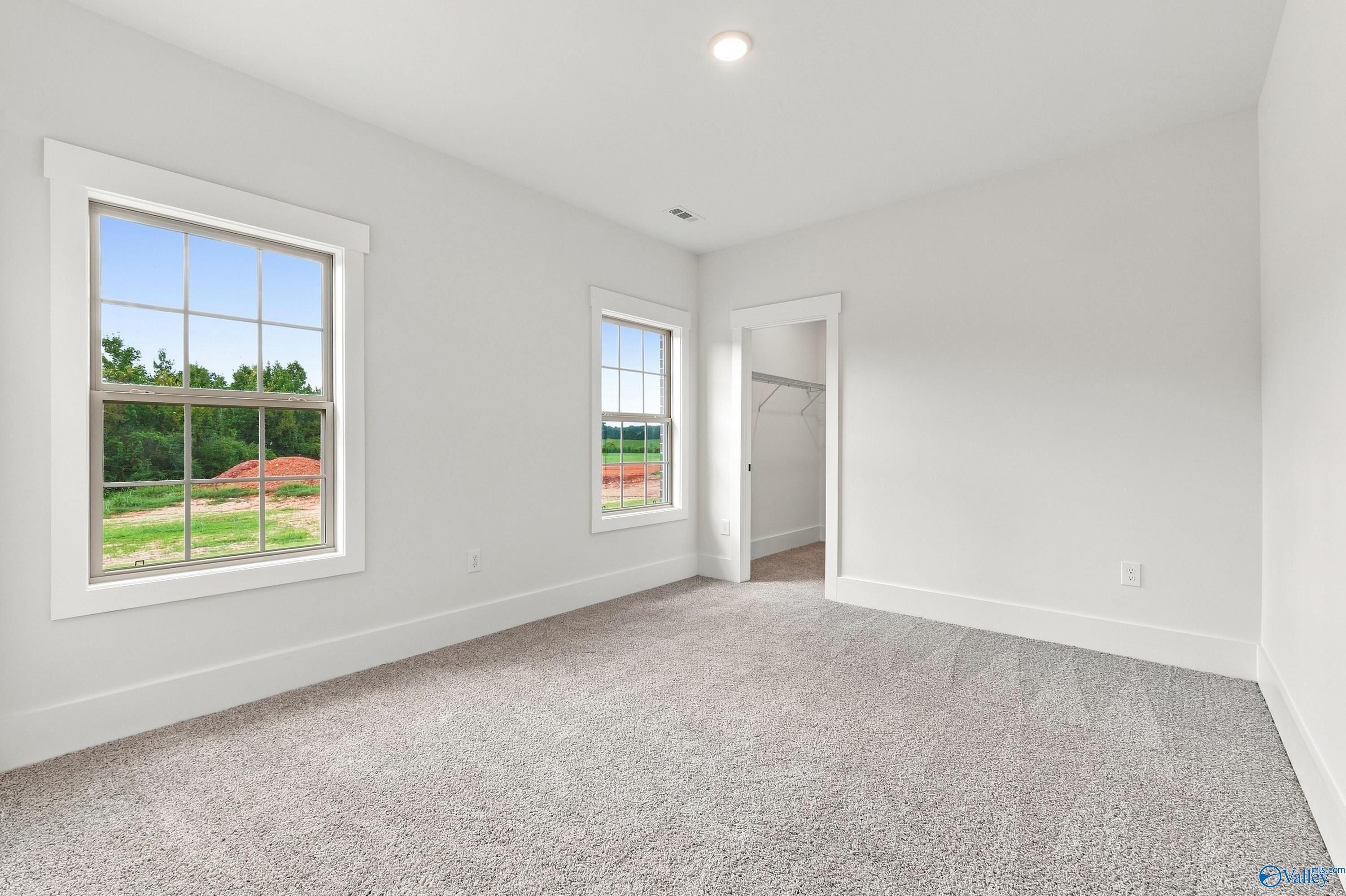 Bright bedroom with new carpet and double windows overlooking backyard in Davidson Homes Valencia plan, Huntsville