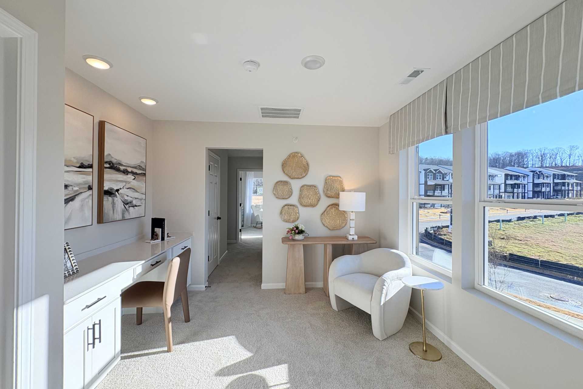 Bright home office in Hemingway community, Cumming Georgia featuring white desk, armchair, woven wall art, and scenic window views
