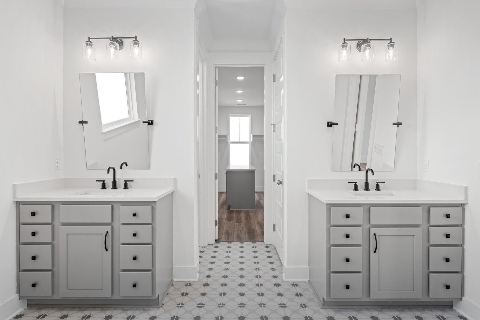 Modern double vanity bathroom with gray shaker cabinets, round mirrors, chrome faucets, and patterned tile floor in Davidson Homes The Alston A, Murfreesboro
