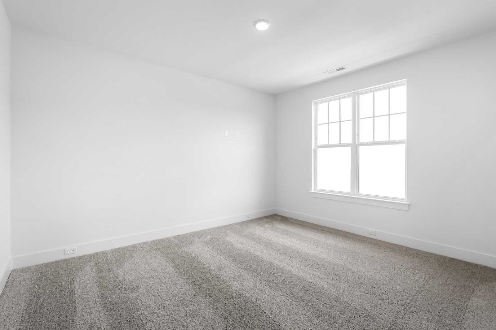 Bright empty secondary bedroom with large window, white walls, and plush carpet in The Hathaway 4-bedroom home, Murfreesboro, TN