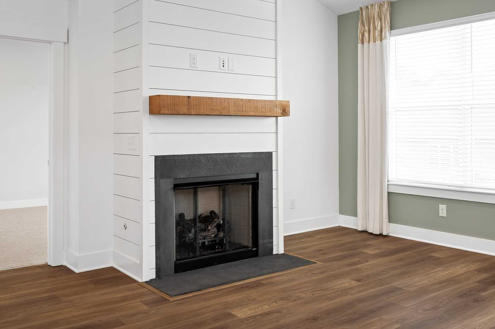 Cozy shiplap fireplace with wooden mantle, slate surround, and gas logs in living room of 4-bedroom Davidson Homes Ridgeport, Gallatin TN