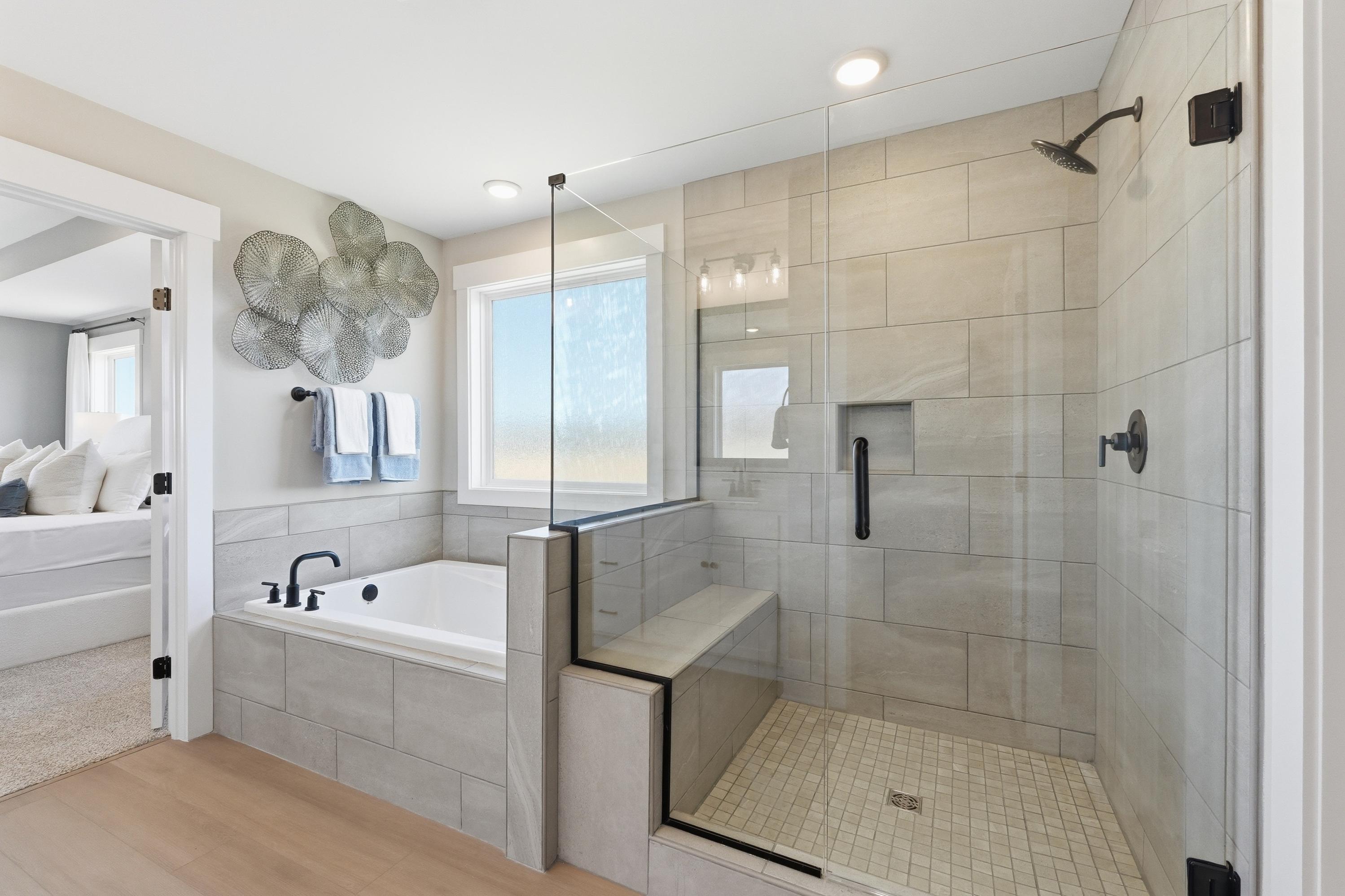 Spacious master bathroom at Berry Cove in New Market Alabama with freestanding tub glass shower and tiled walls