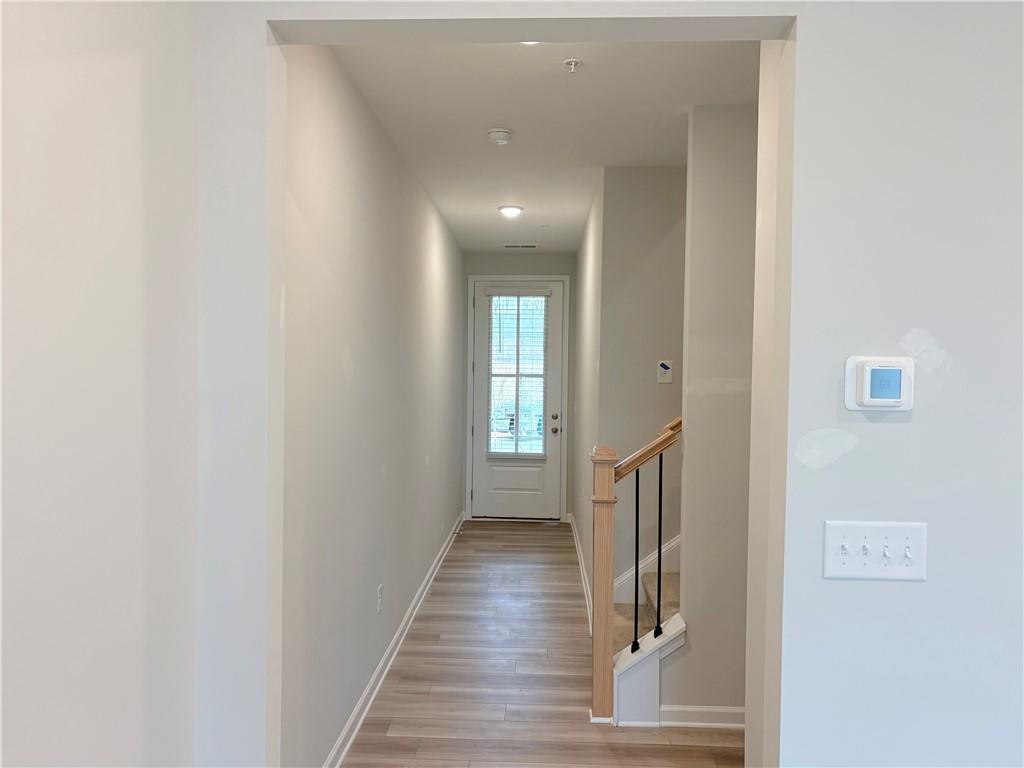 Bright hallway with hardwood floors, oak staircase, and glass door in The Wake E 3-bedroom home, Cumming, Georgia