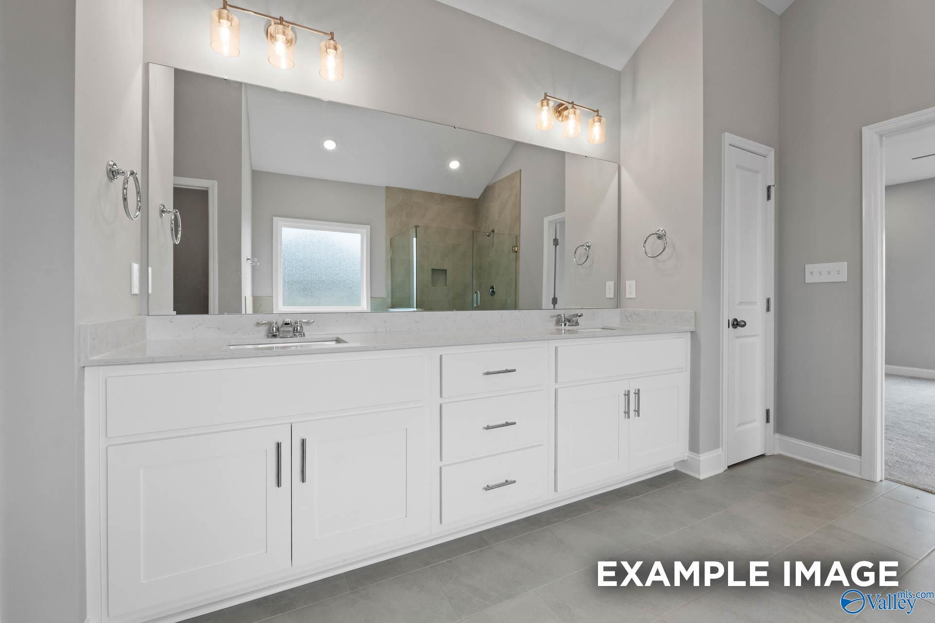 Elegant master bathroom double vanity with white cabinets, large mirror, and frosted glass shower in Davidson Homes The Finleigh, Harvest, Alabama