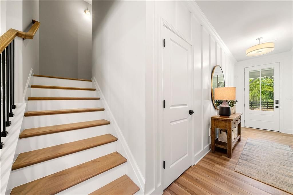 Elegant wooden staircase with black iron balusters and shiplap walls in foyer of Davidson Homes The Willow B, Riverwood, Dallas, Georgia