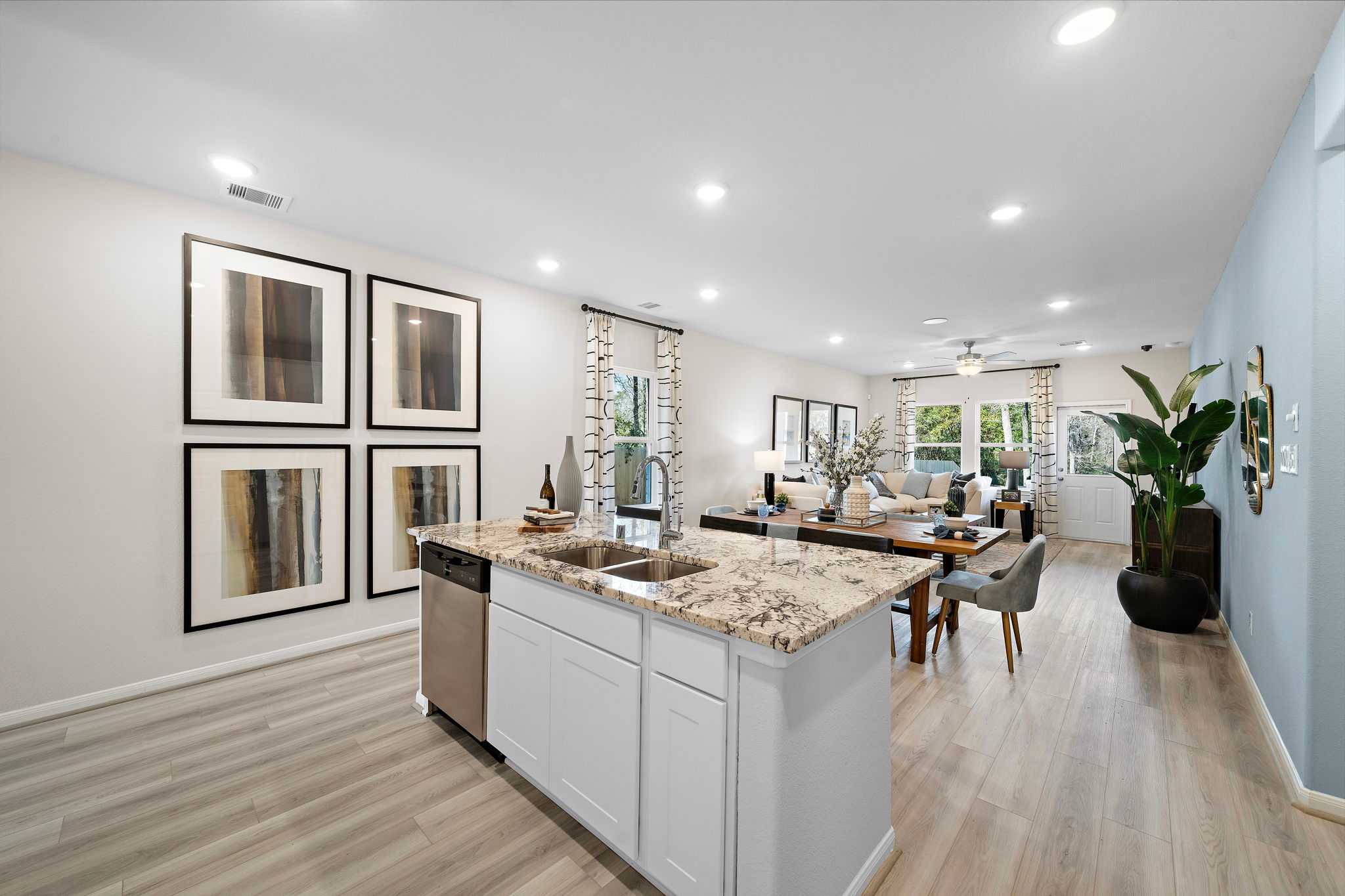 Spacious open-concept kitchen dining area at Lakes at Black Oak in Magnolia TX with granite island white cabinets hardwood floors