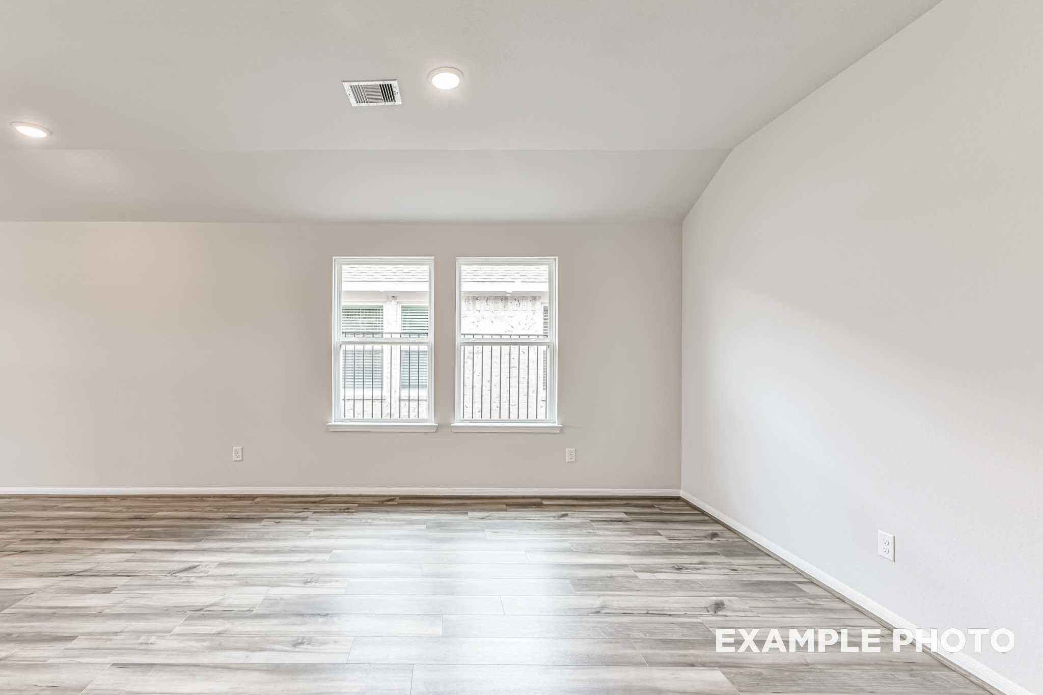Spacious empty living room in The Laguna C with hardwood floors, white walls, large windows, and recessed lighting