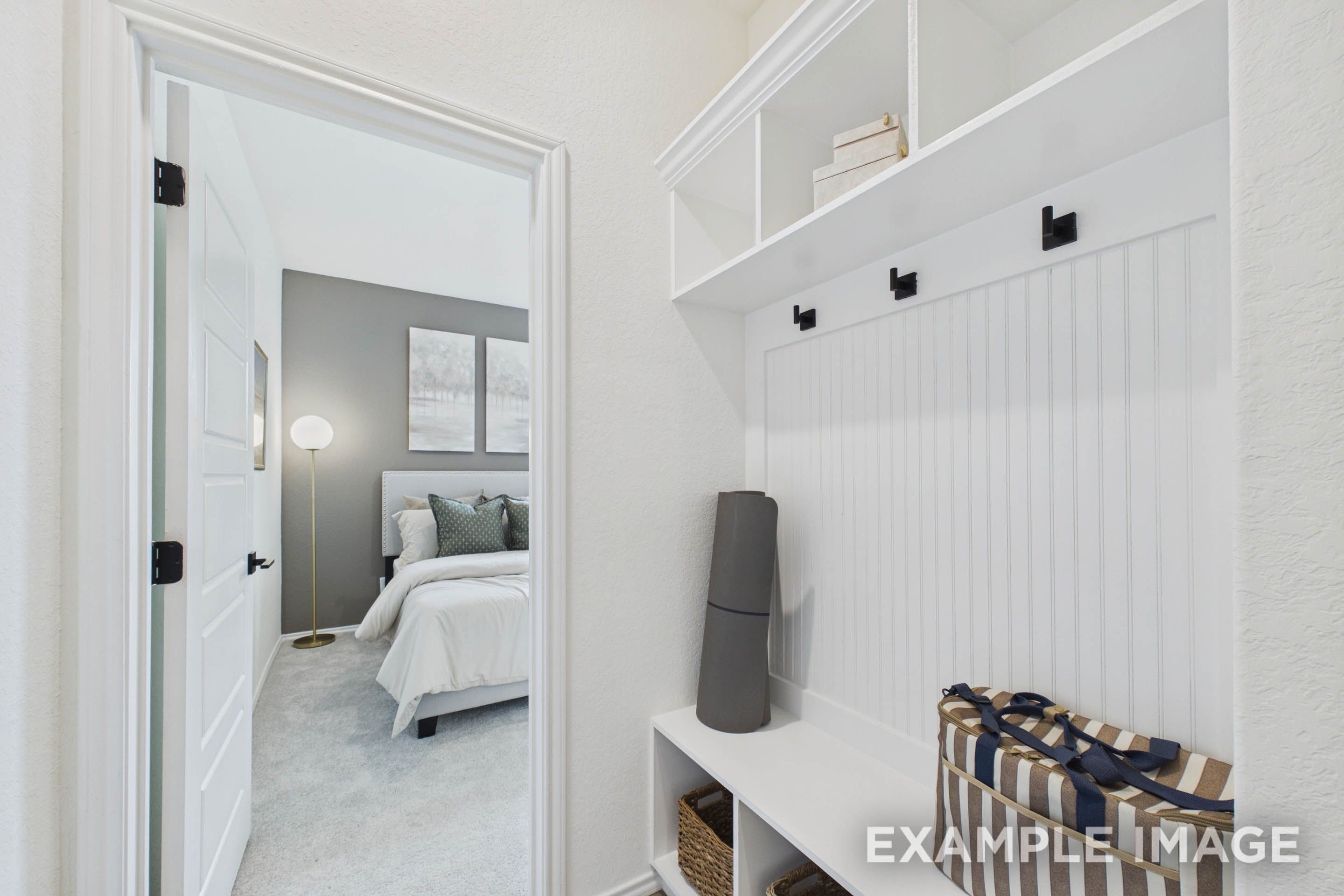 Built-in mudroom bench and storage in The Laurel G floor plan leading into a master suite with gray accent wall.