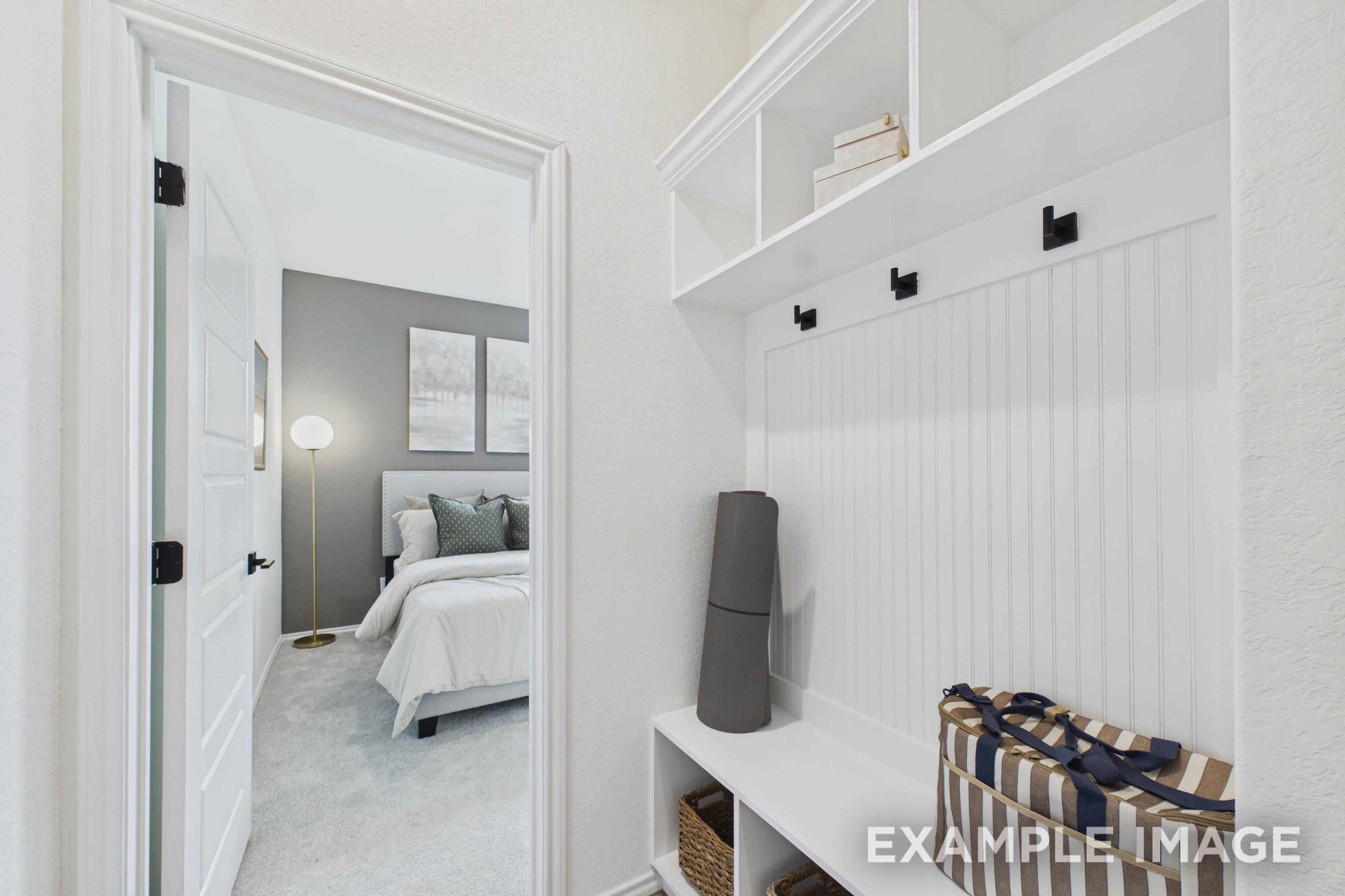 Built-in mudroom bench and storage in The Laurel G floor plan leading into a master suite with gray accent wall.
