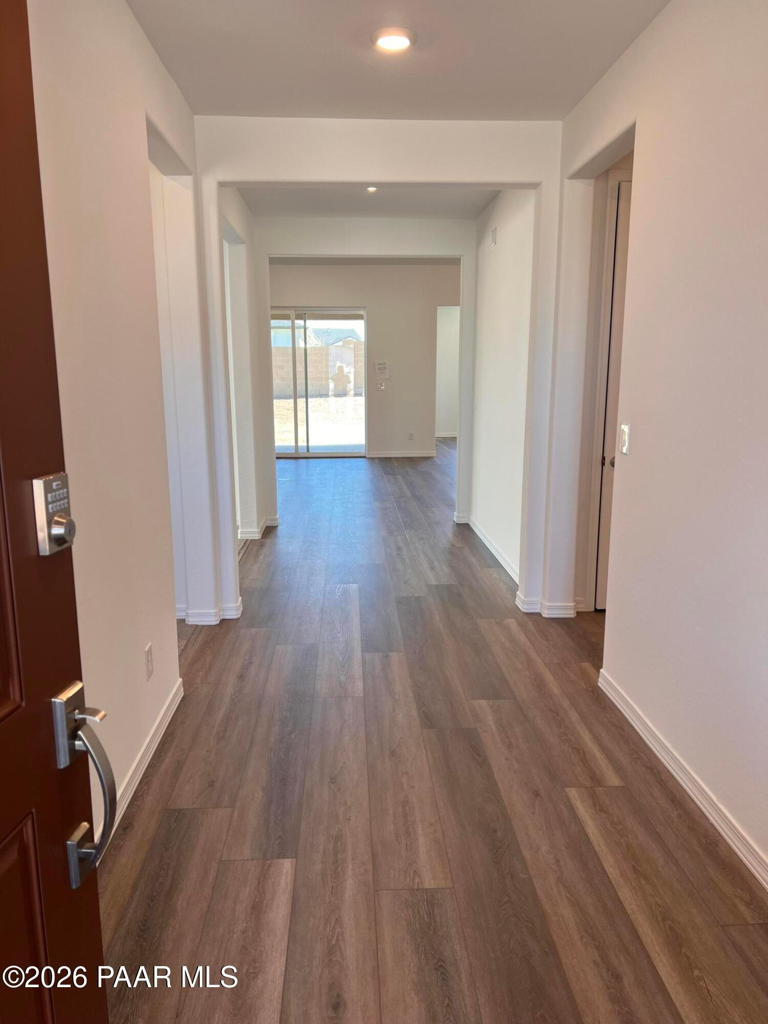 Spacious entry hallway with hardwood-look flooring, side doors, and sliding glass to backyard in 3-bed Davidson Homes Sunrise II A, Prescott AZ