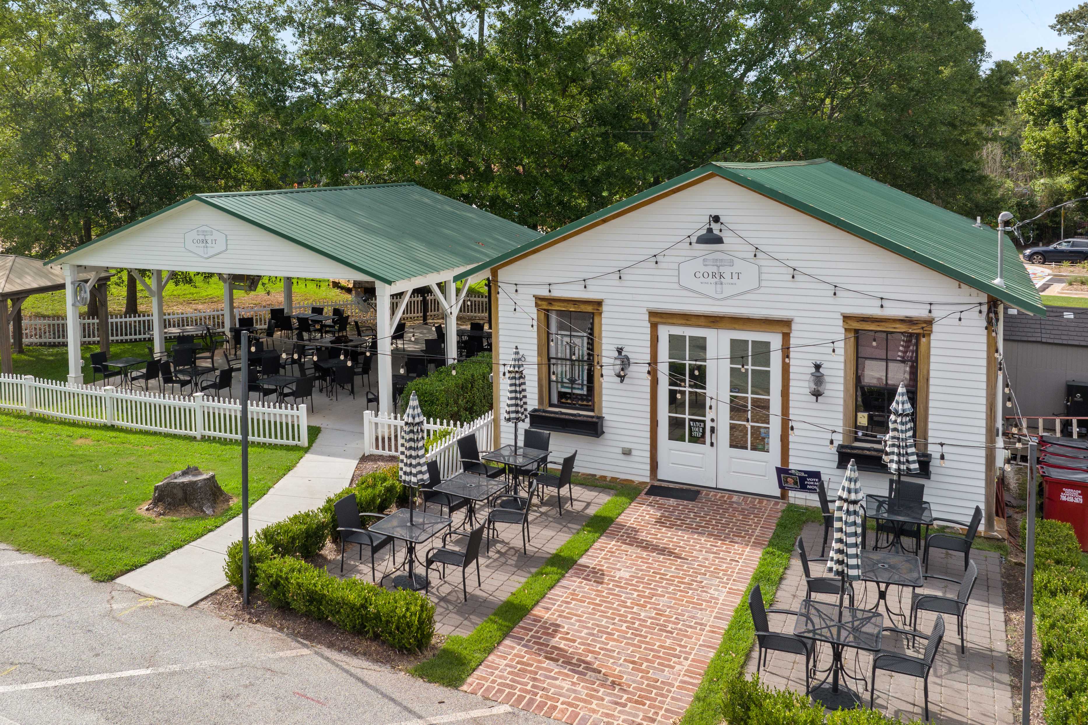 Charming cafe with green roof and pavilion at Wehunt Meadows in Hoschton Georgia featuring outdoor umbrella seating and brick patio