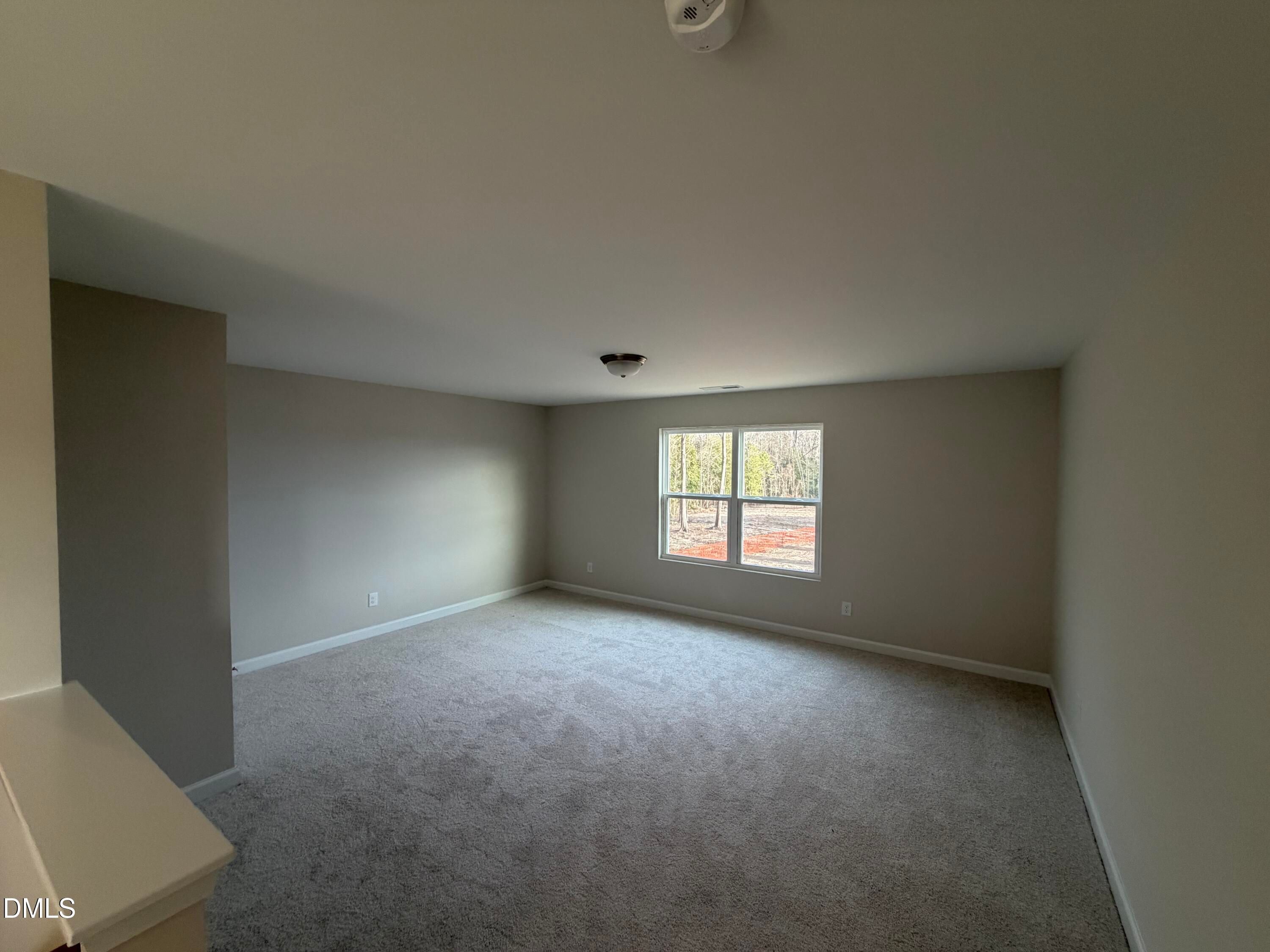 Empty upstairs bedroom with large windows, beige walls, carpet floor, and ceiling fan in Davidson Homes The Ash B, Lillington, NC
