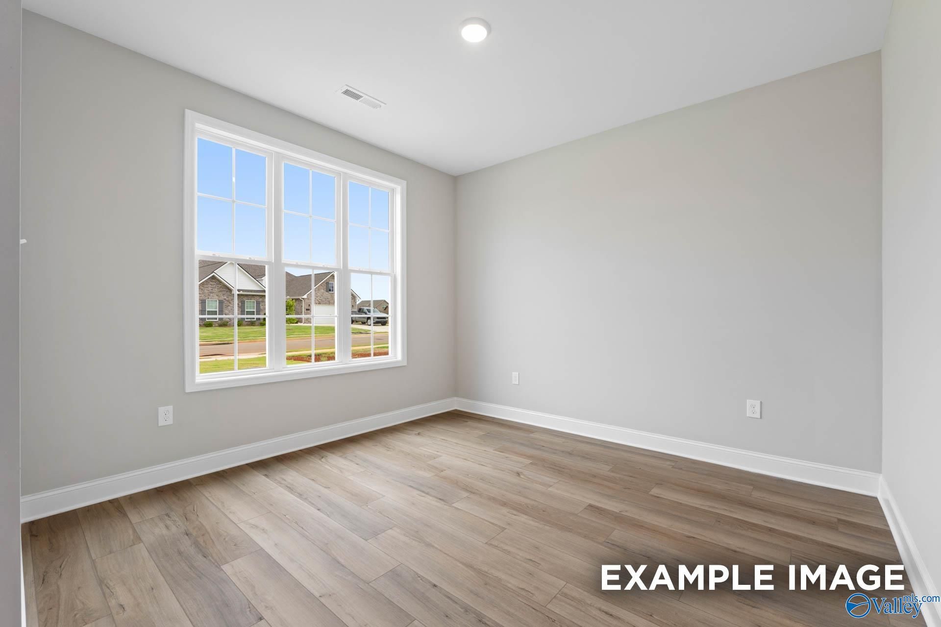 Bright secondary bedroom with large window overlooking green lawn and homes in The Finleigh, Harvest, Alabama