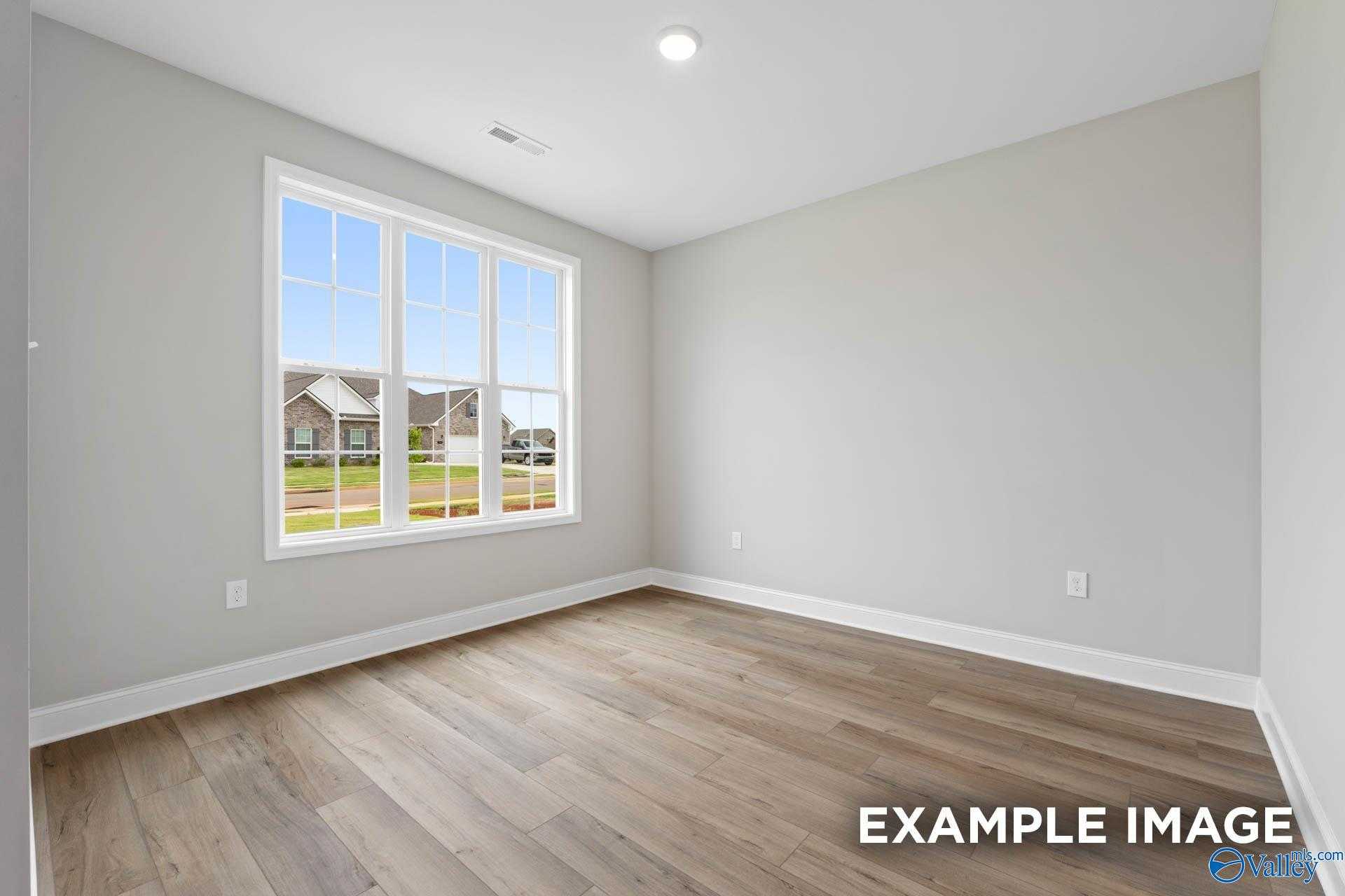 Bright secondary bedroom with large window overlooking green lawn and homes in The Finleigh, Harvest, Alabama