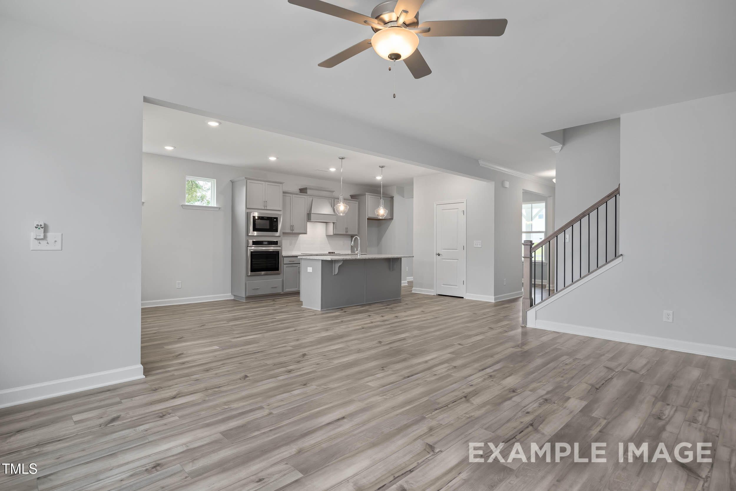 Open-concept kitchen with gray island, double ovens, and hardwood floors in Davidson Homes The Willow E, Angier, NC