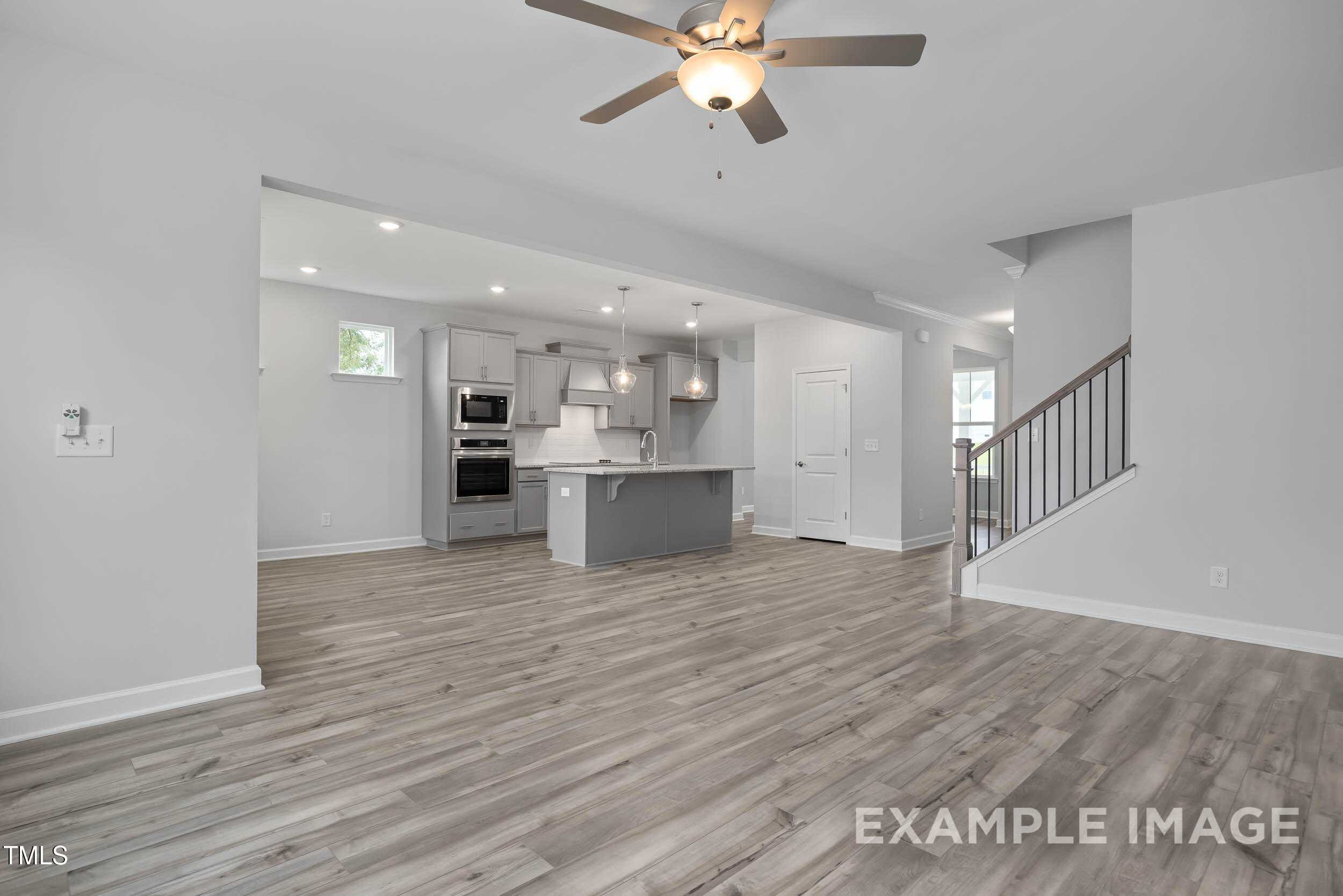 Open-concept kitchen with gray island, double ovens, and hardwood floors in Davidson Homes The Willow E, Angier, NC