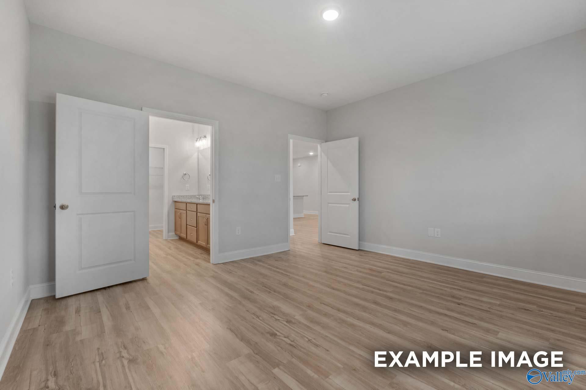 Spacious master bedroom with gray walls, hardwood floors, and open en-suite bathroom featuring double vanity in Davidson Homes The Cumberland B, Decatur, Alabama
