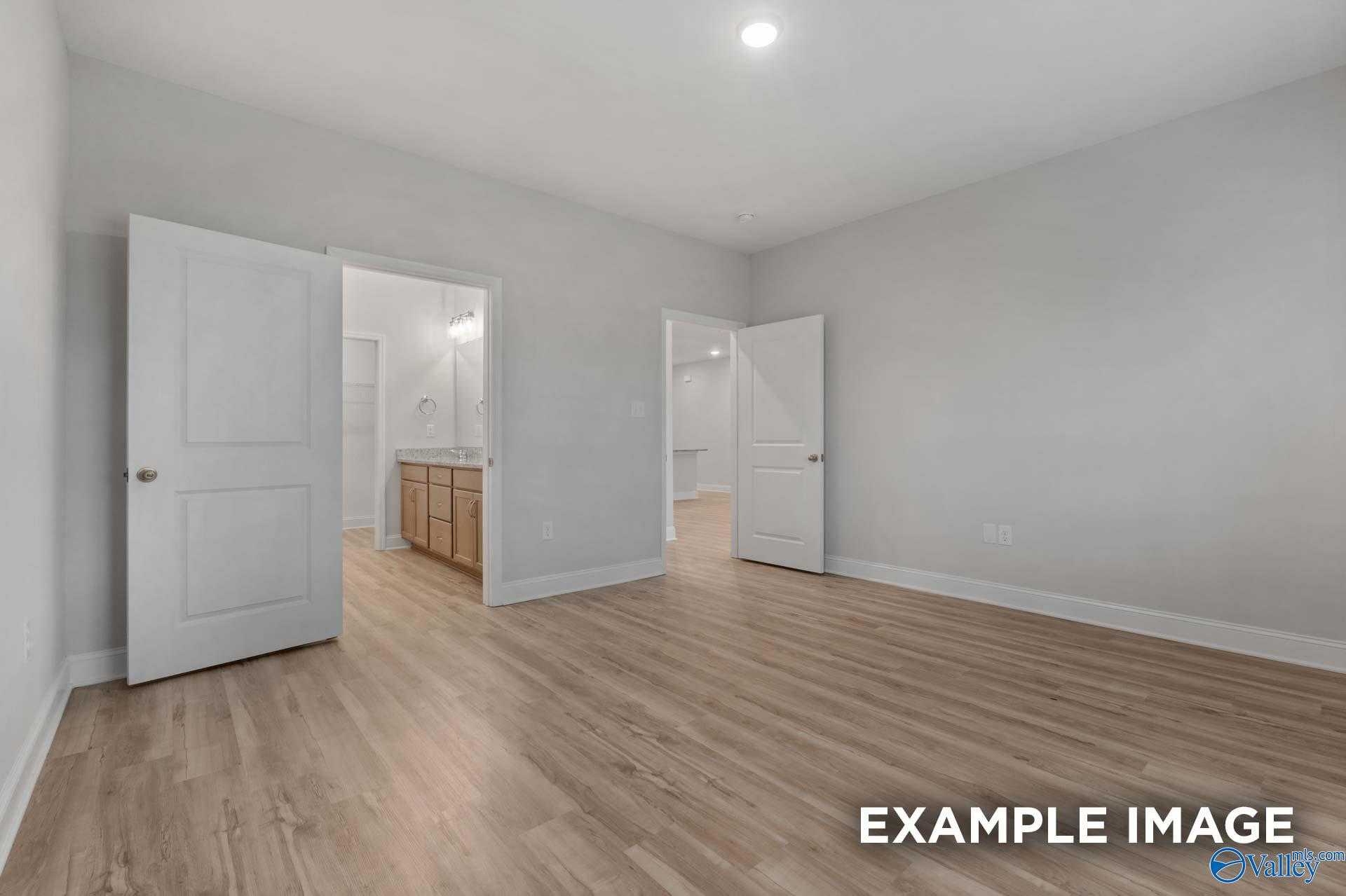 Spacious master bedroom with gray walls, hardwood floors, and open en-suite bathroom featuring double vanity in Davidson Homes The Cumberland B, Decatur, Alabama