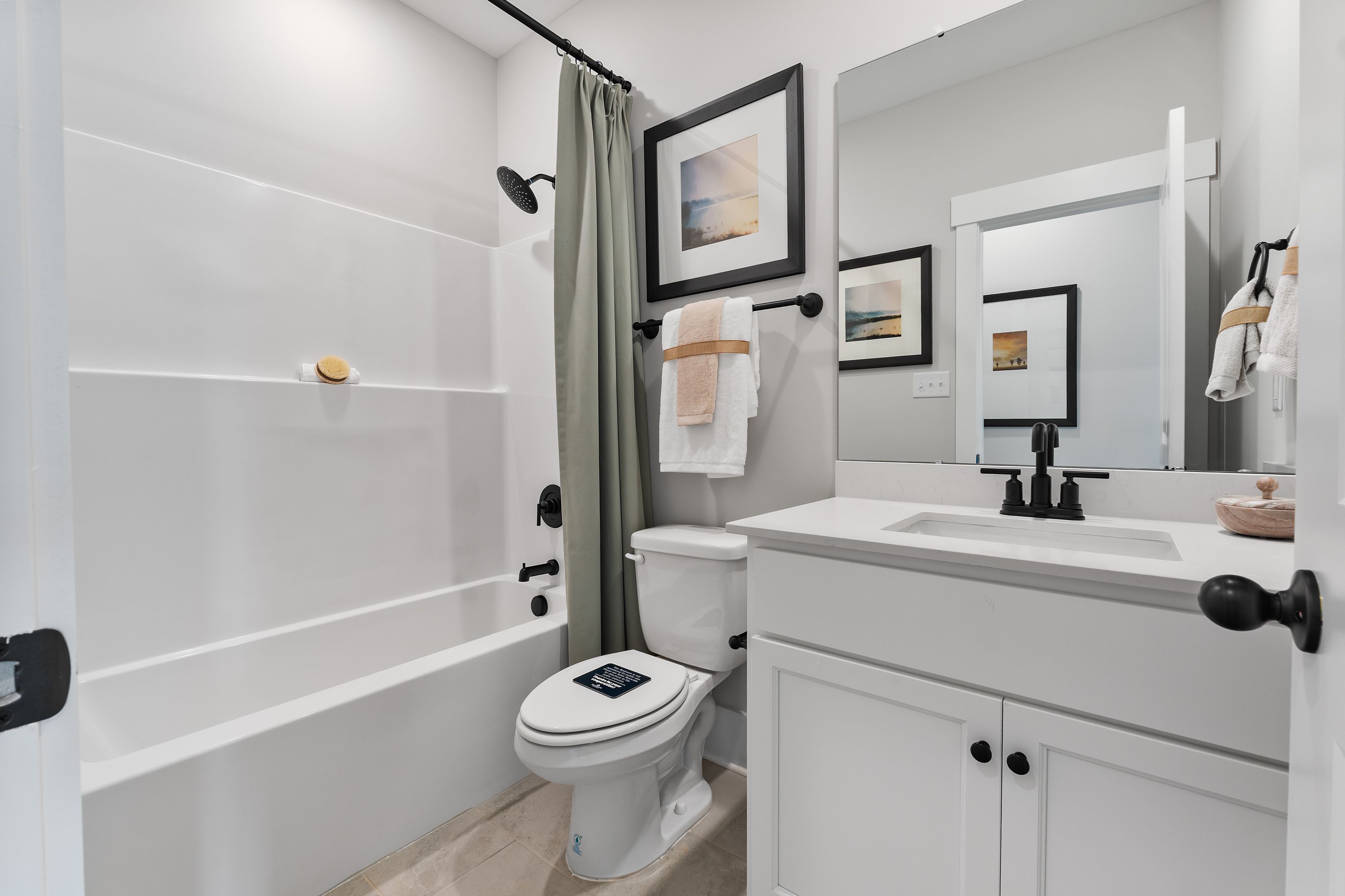 Spacious bathroom at River Road Estates in Decatur AL with white tub, shower curtain, modern vanity and framed art