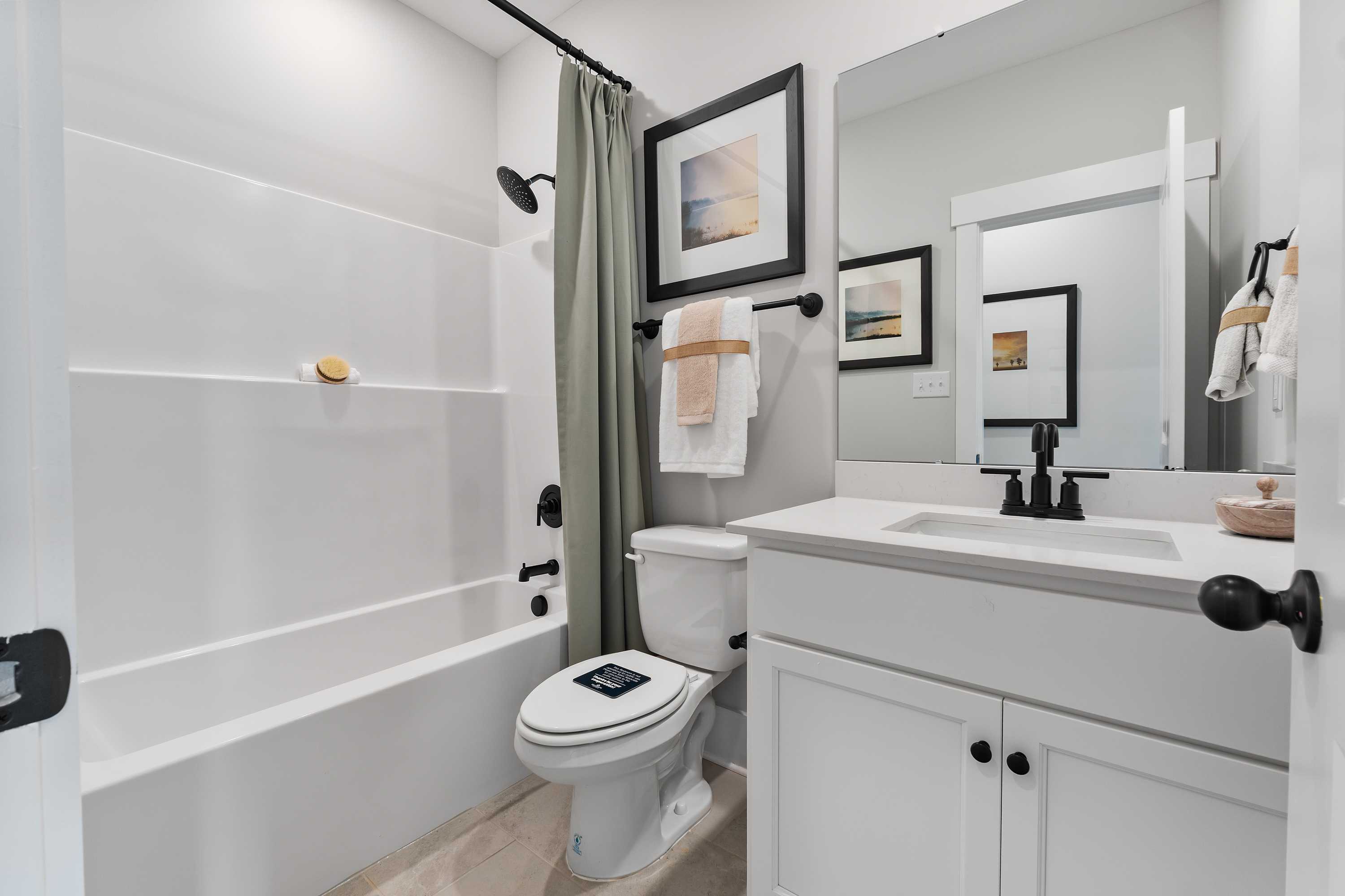 Spacious bathroom at River Road Estates in Decatur AL with white tub, shower curtain, modern vanity and framed art