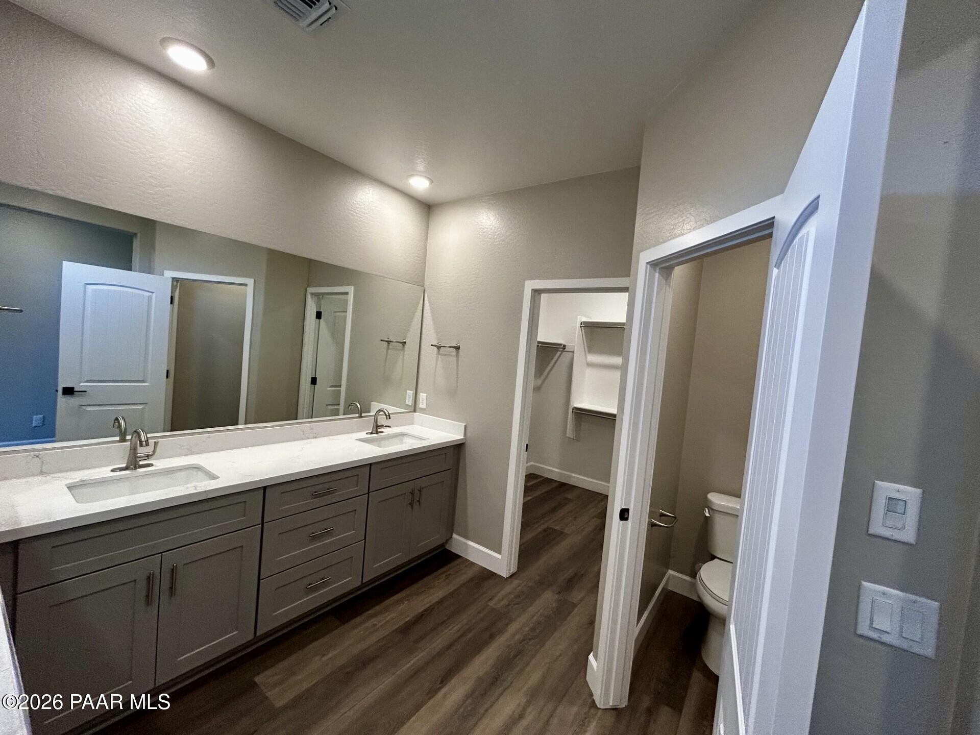 Modern primary bathroom with dual vanity, quartz countertops, and walk-in closet in The Harmony C at Pronghorn Ranch.