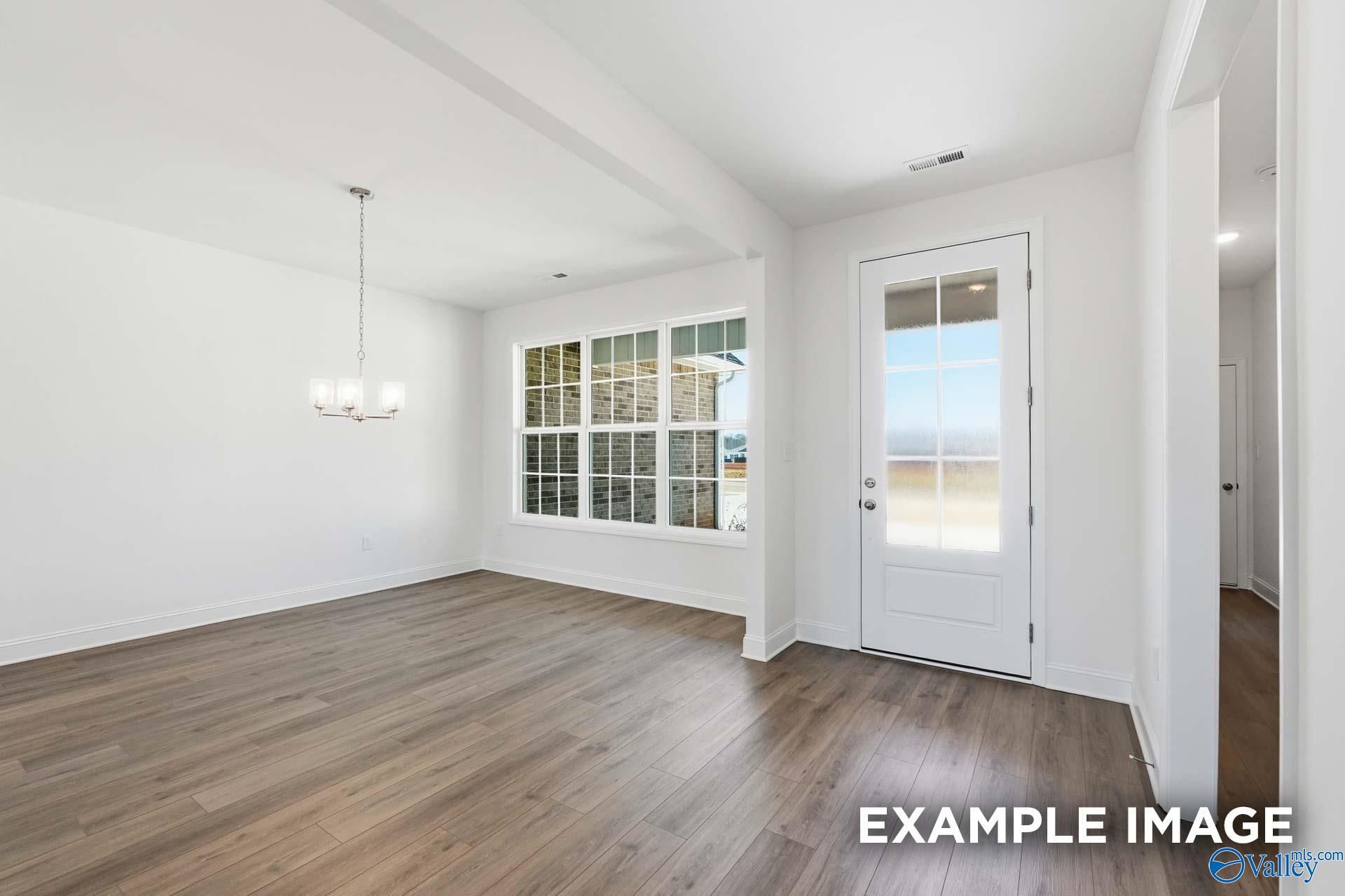 Bright dining area with wood-look flooring and glass door in The Valencia floor plan, Briercreek, Meridianville, Alabama.
